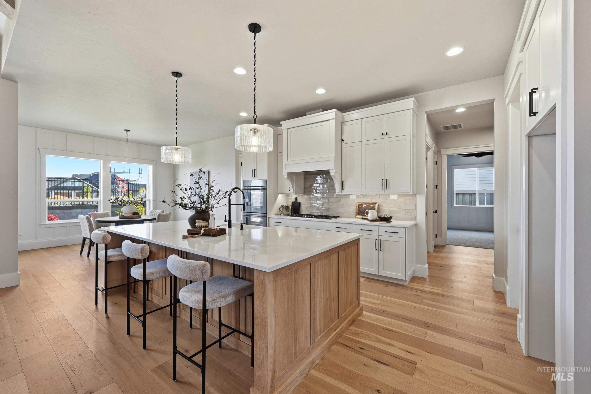 Kitchen featuring white cabinets, backsplash, hanging light fixtures, recessed lighting, and light wood finished floors