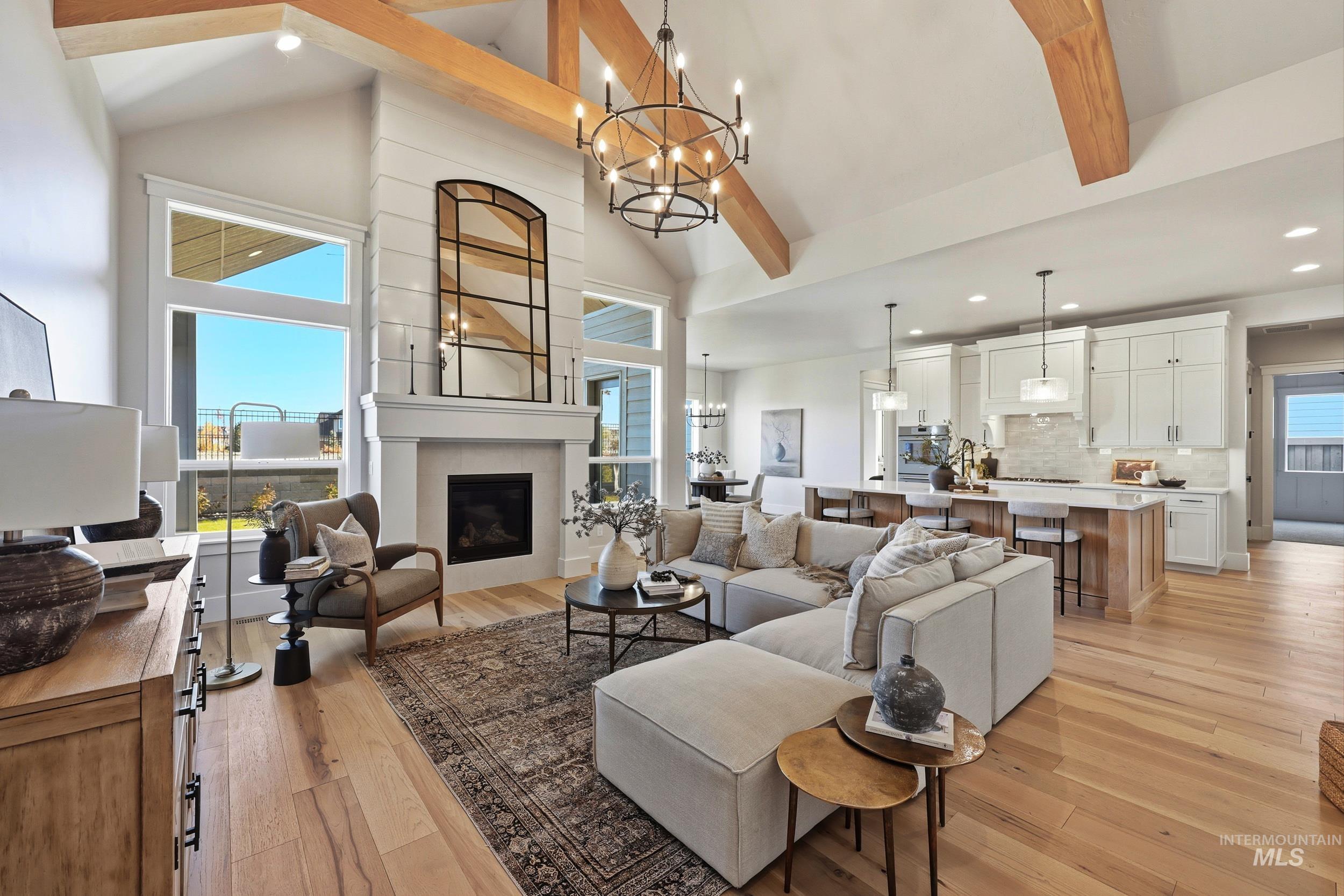 Living room with beamed ceiling, a chandelier, light wood finished floors, high vaulted ceiling, and recessed lighting