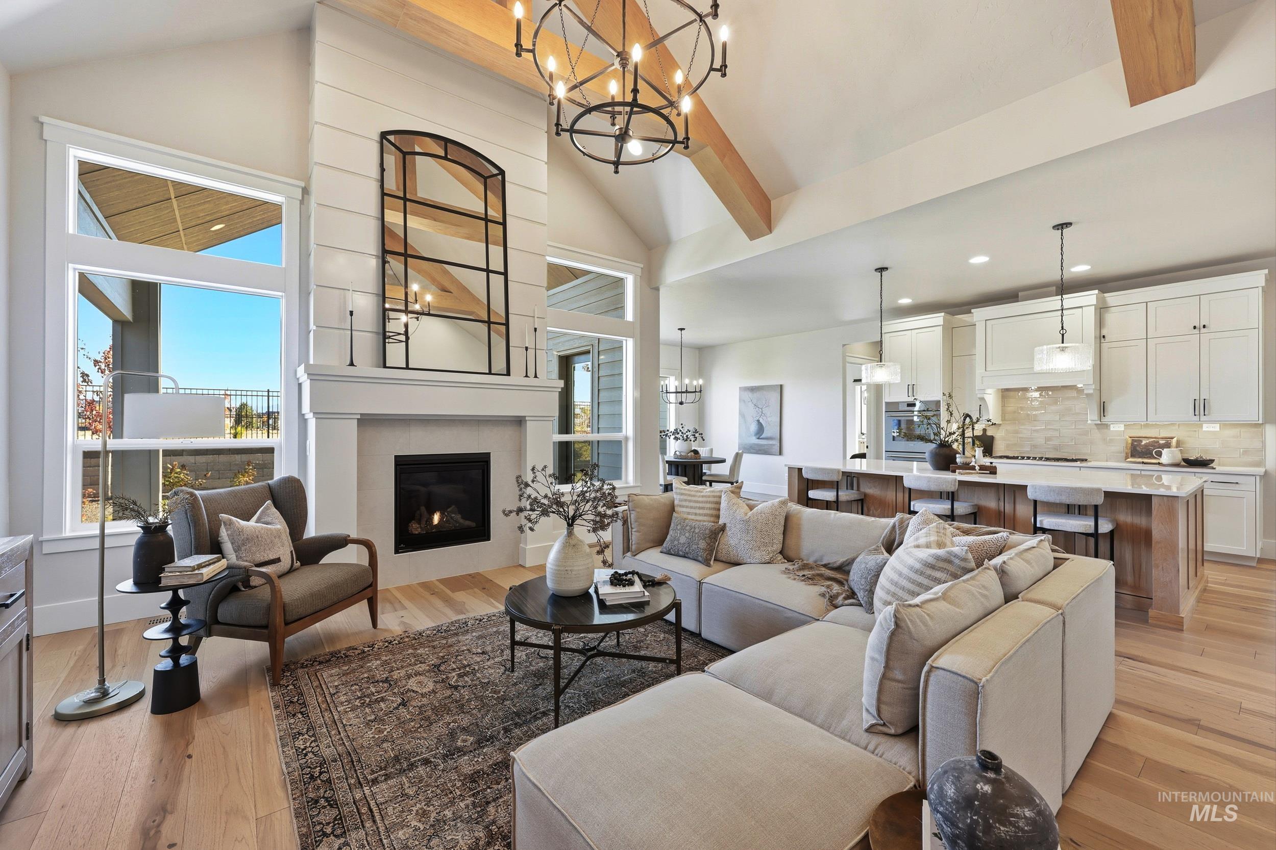 Living area featuring light wood finished floors, a chandelier, plenty of natural light, and high vaulted ceiling