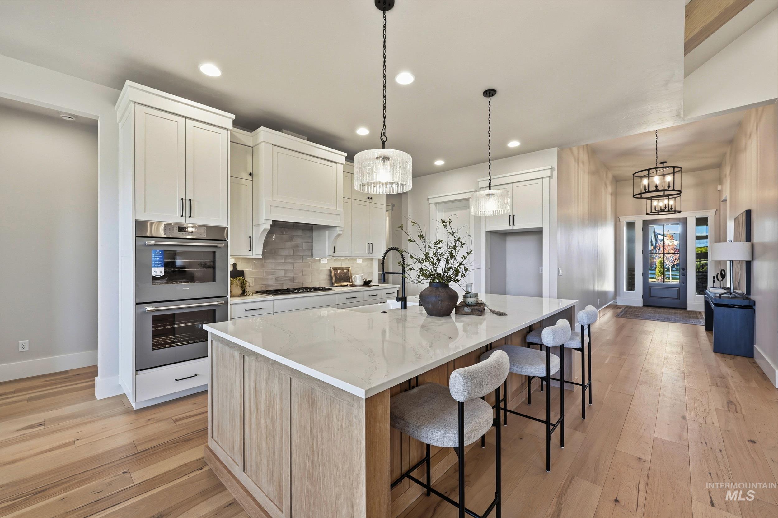 Kitchen with backsplash, white cabinets, appliances with stainless steel finishes, a kitchen bar, and recessed lighting