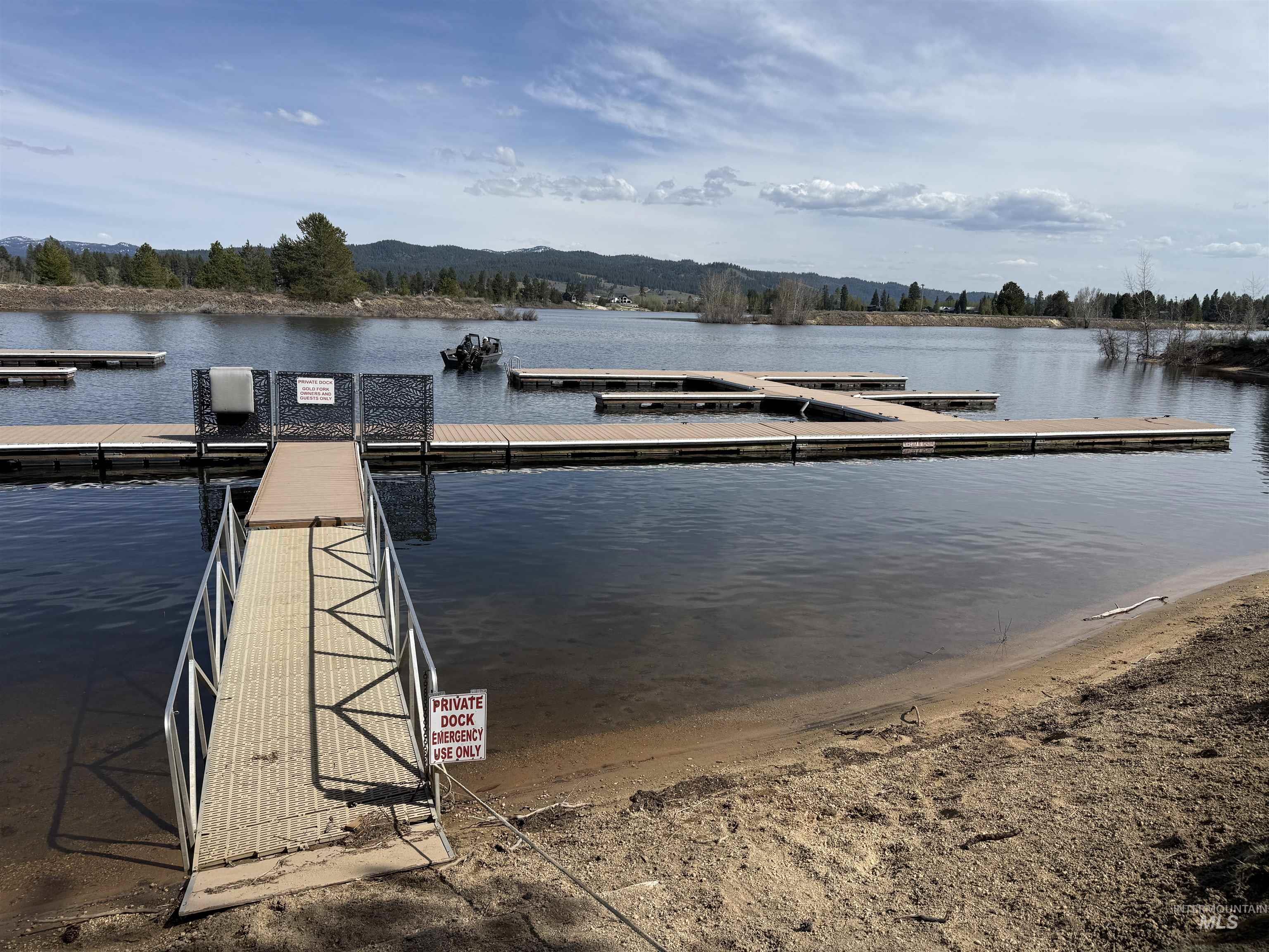Private dock access featuring a metal ramp, multiple floating dock sections, and a sandy shoreline