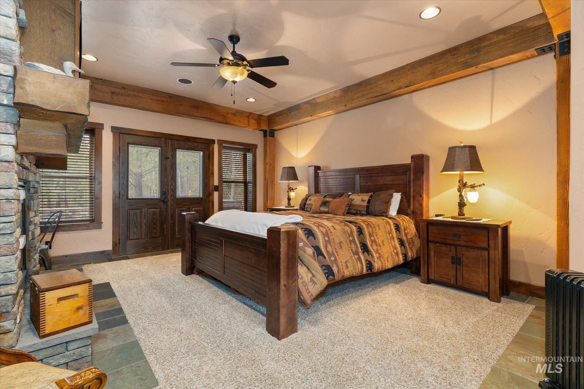 Exposed wood beams accentuating the ceiling, a stone-faced fireplace with a substantial wood mantel, and double wood-frame doors with glass panels