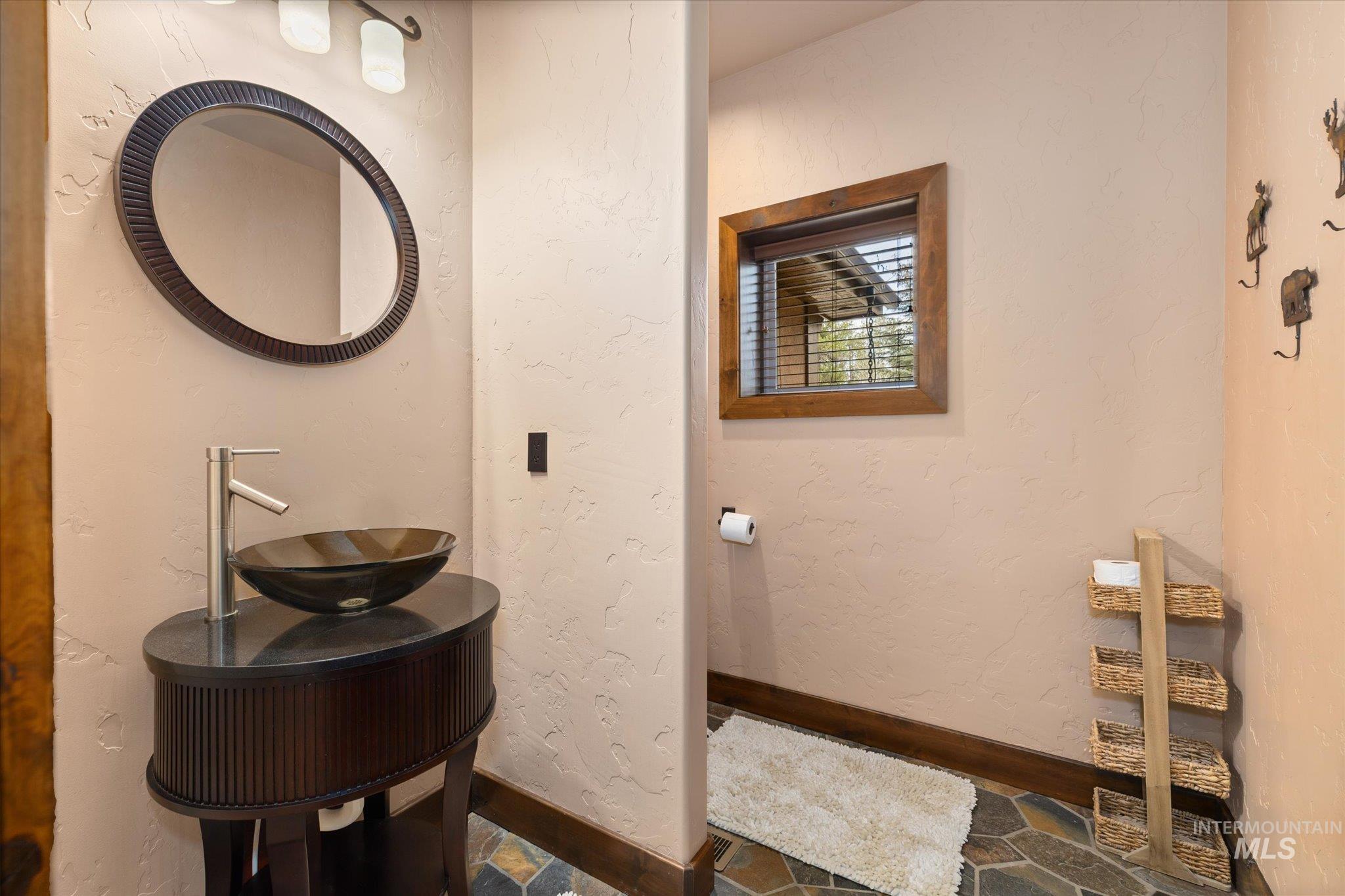 Powder room featuring a vessel sink with a contemporary faucet, an oval mirror, and a wood-framed window
