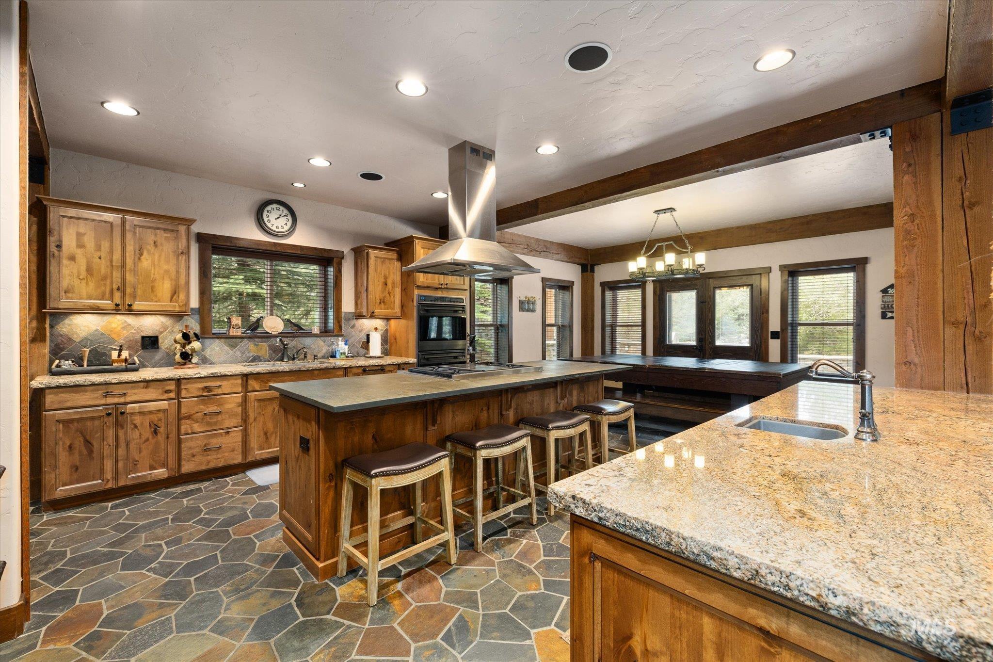 Kitchen featuring wood-finish cabinetry, stone flooring, and recessed lighting