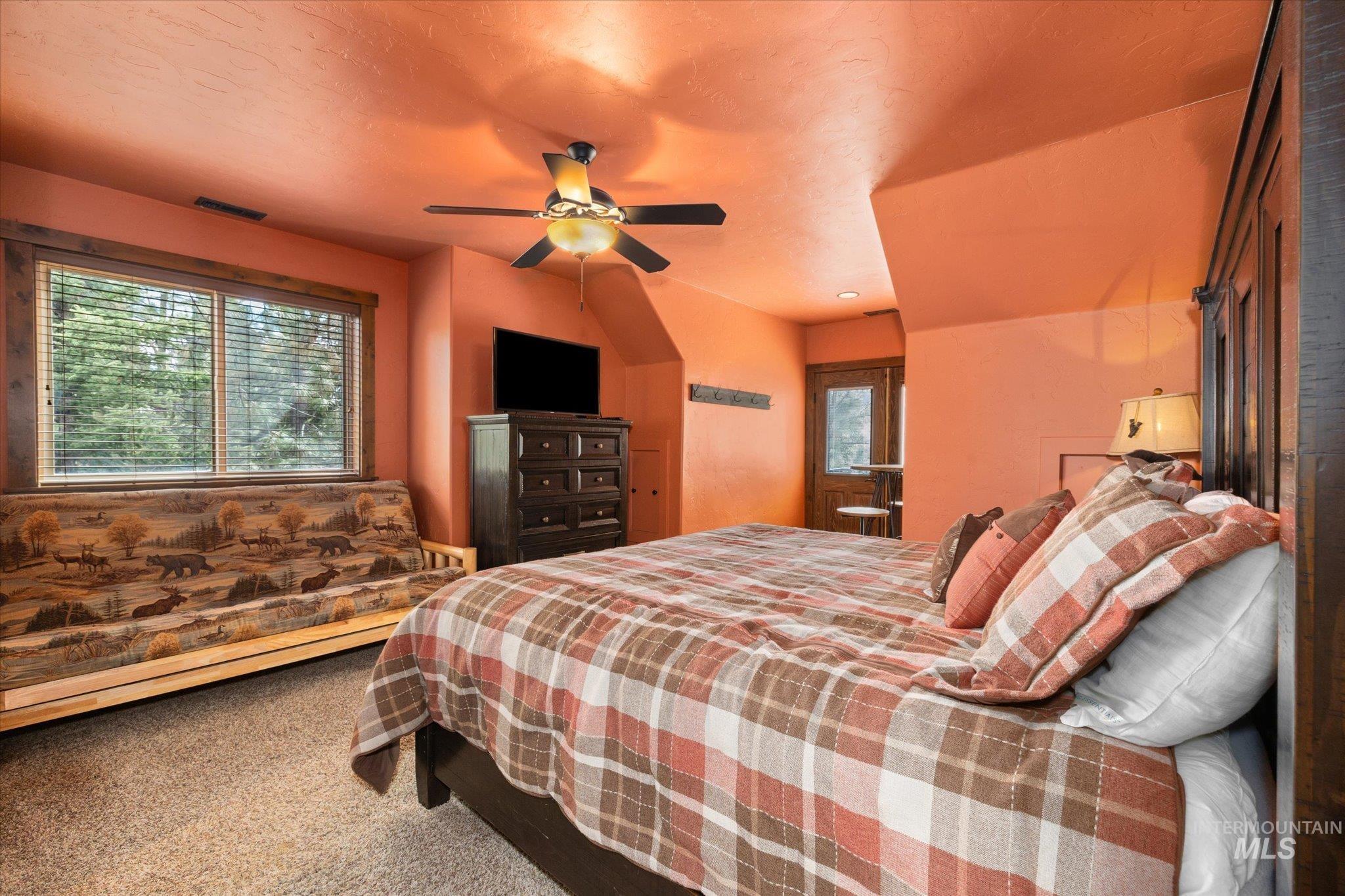 Carpeted room featuring a ceiling fan with light fixture, a window with blinds, and a built-in wooden headboard