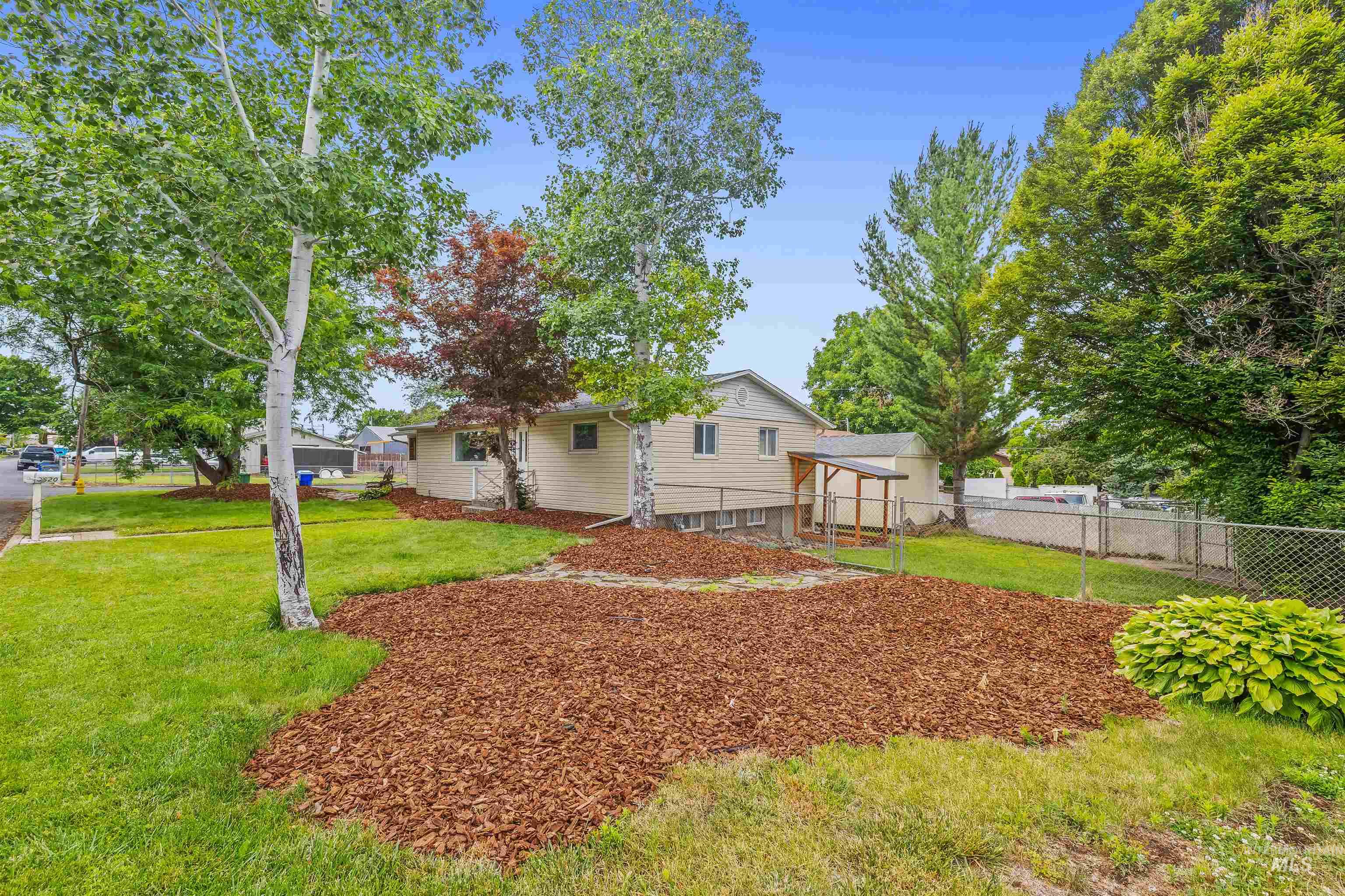 Landscaped front yard featuring mature trees and a mulched bed
