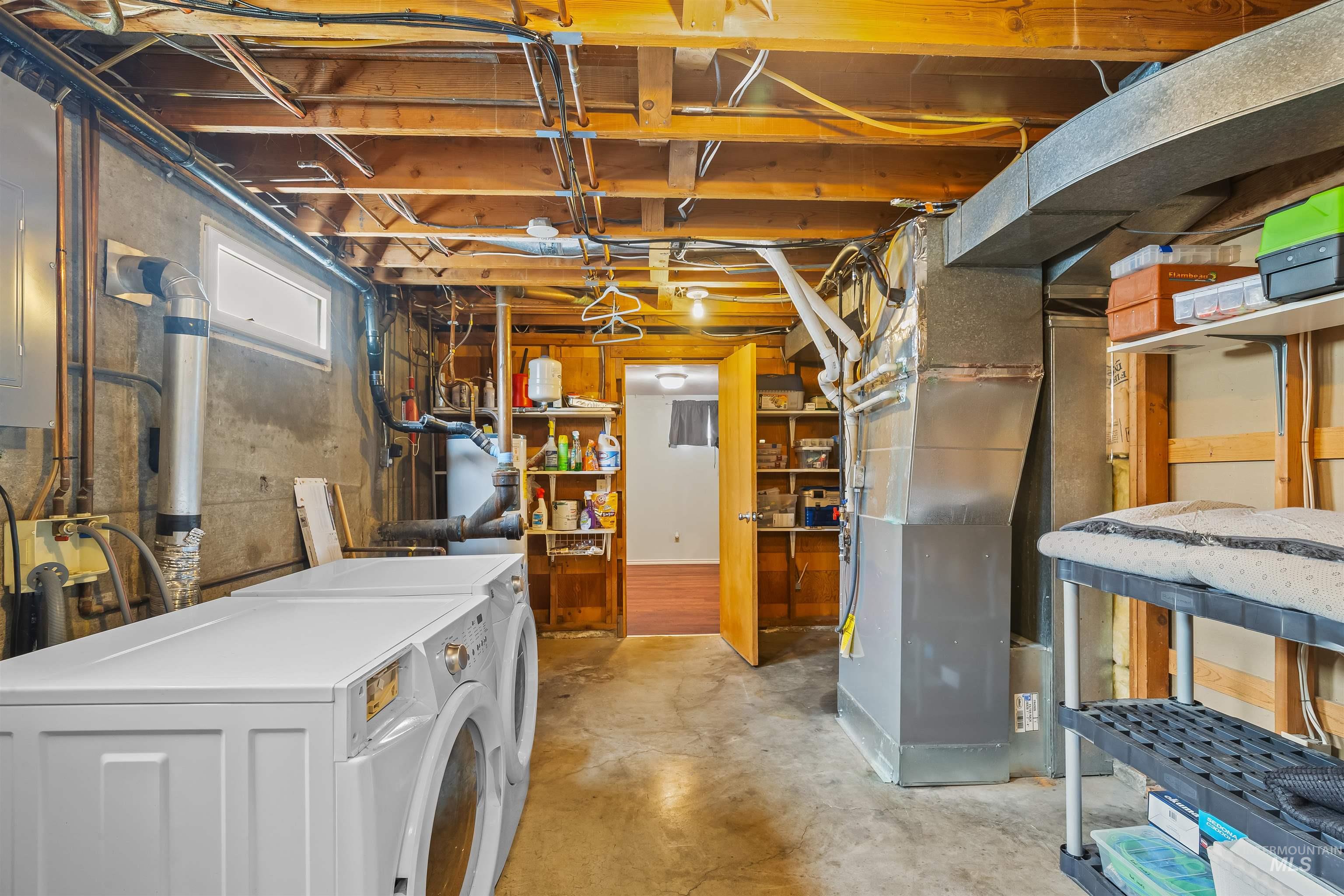 Utility area featuring exposed wood ceiling joists, concrete flooring, a wall-mounted water heater, and a small horizontal window