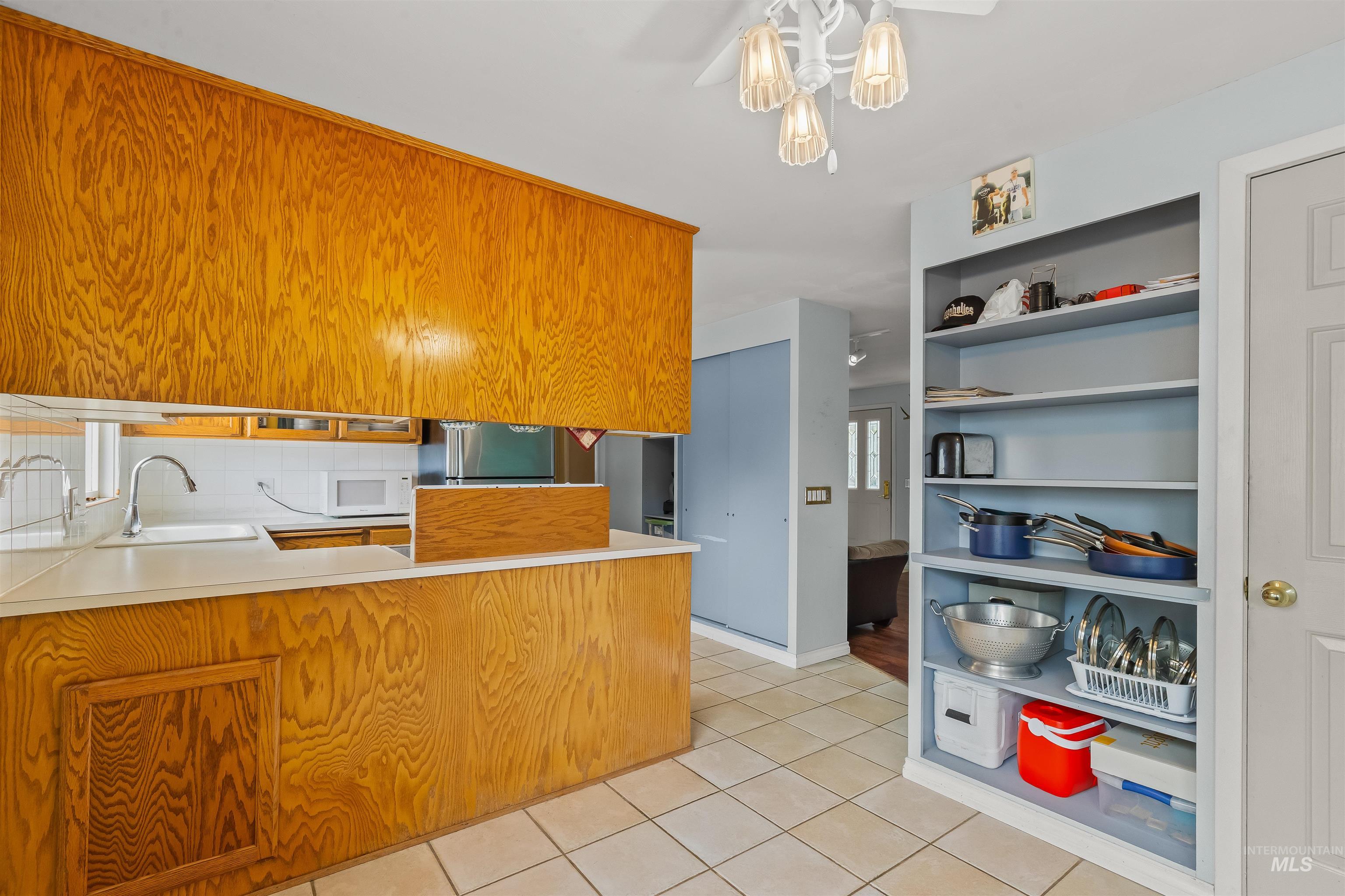 Kitchen featuring wood-finish cabinetry, solid surface countertops, a ceramic tile floor, and a drop-in sink with a gooseneck faucet