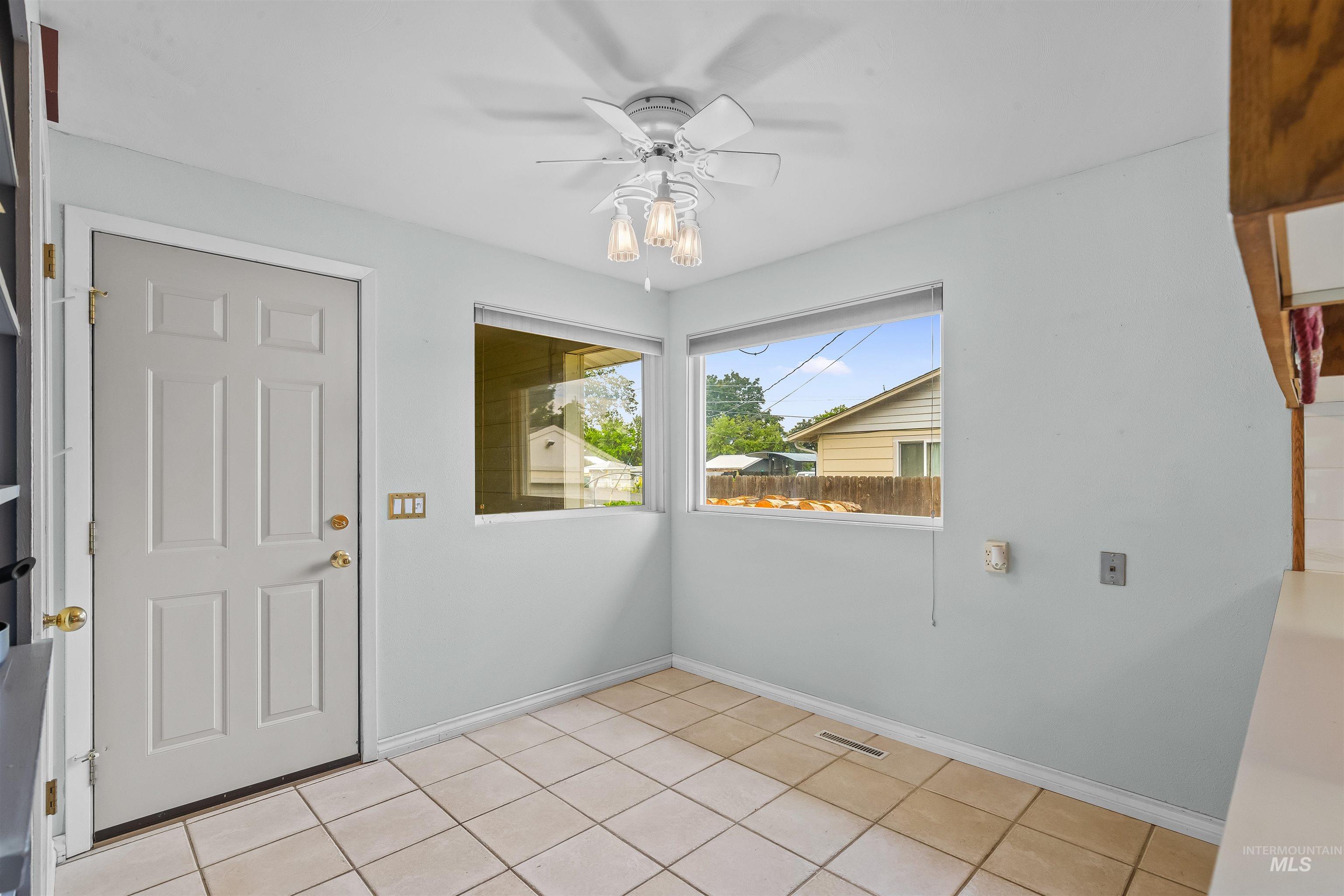 Bright interior space featuring a multi-paneled door, tile flooring, and multiple windows