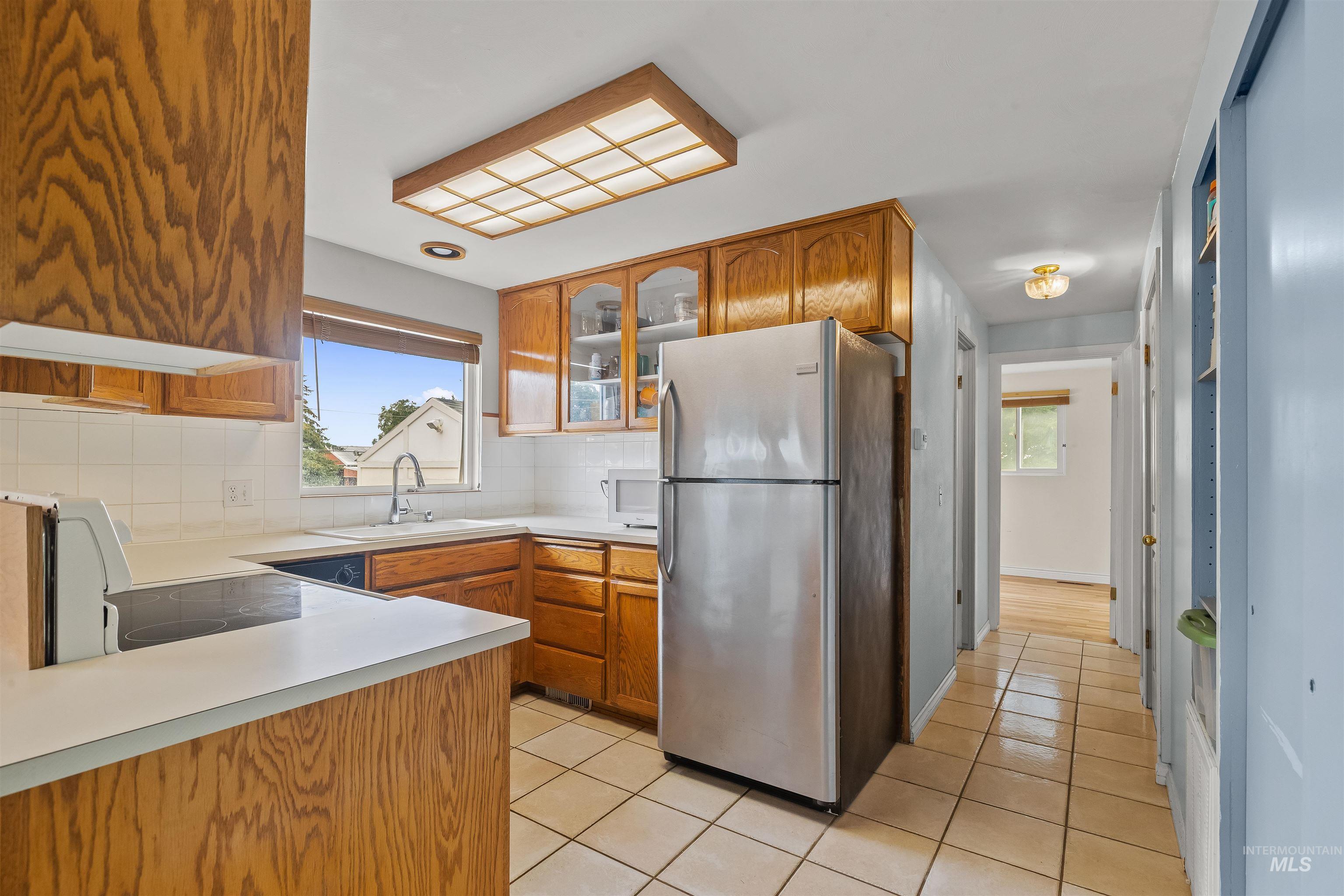 Kitchen featuring wood cabinetry, white countertops, a tiled backsplash, and ceramic tile flooring