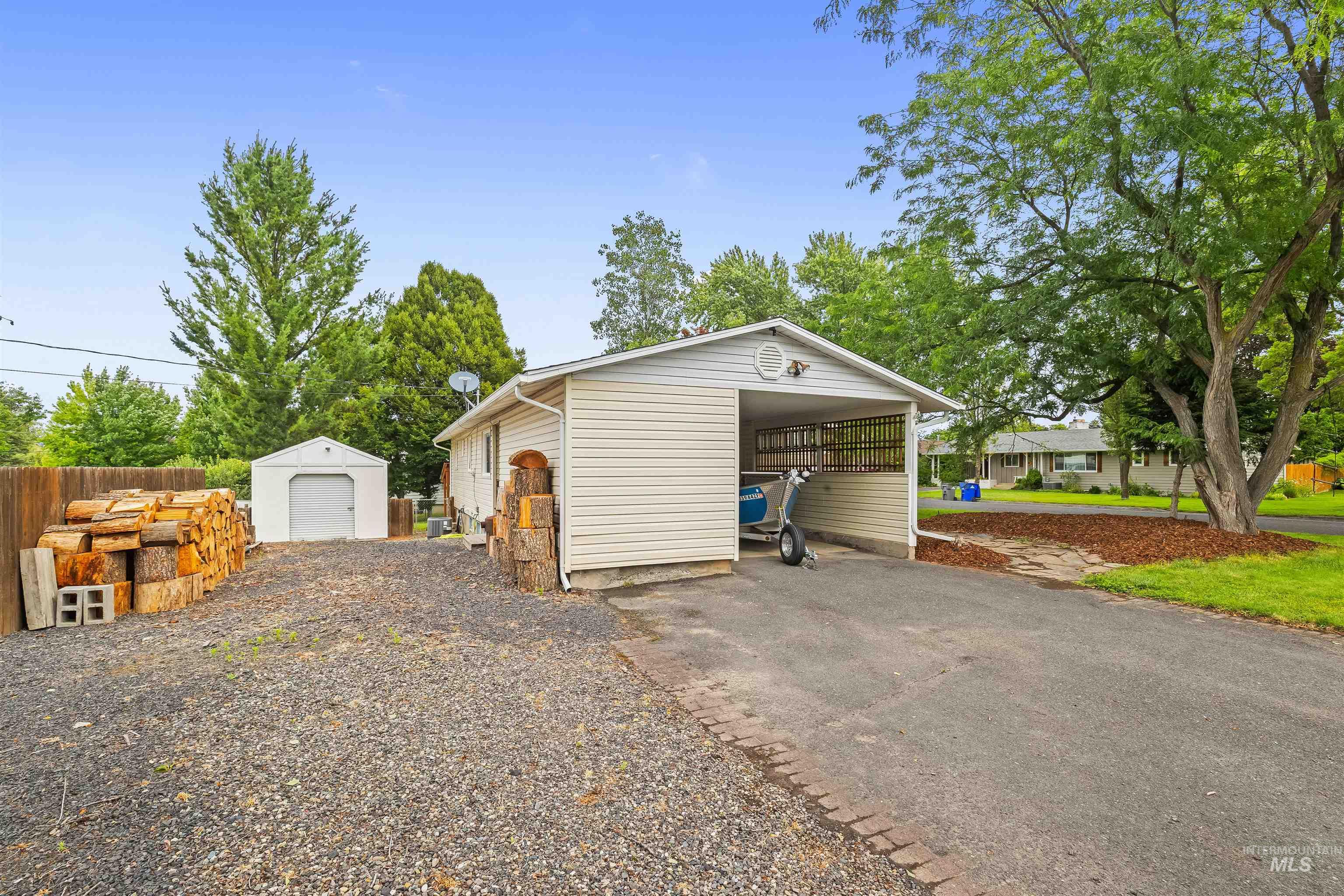Exterior featuring a carport, detached shed, and gravel driveway
