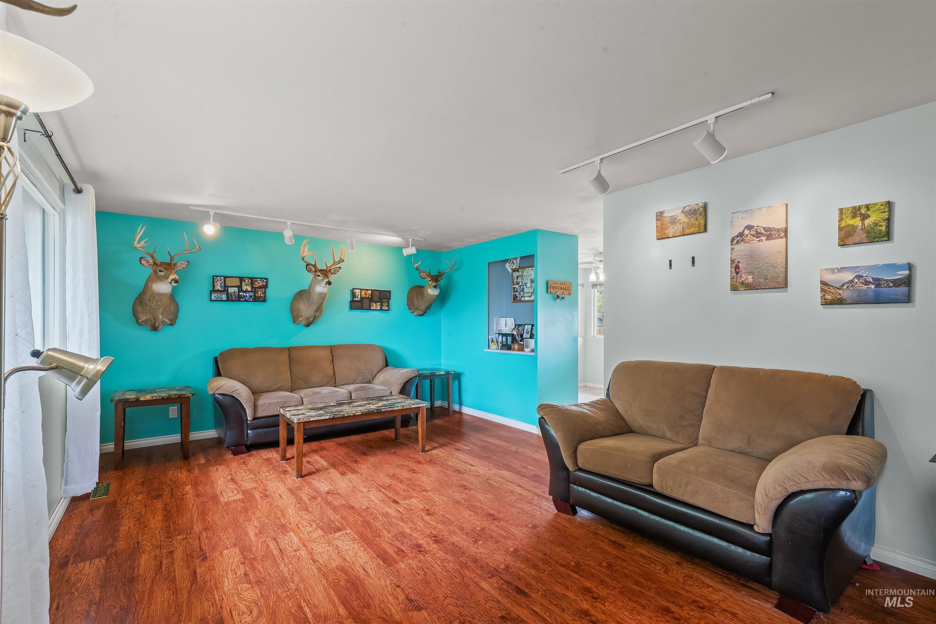 Spacious living area featuring wood-finish flooring and track lighting
