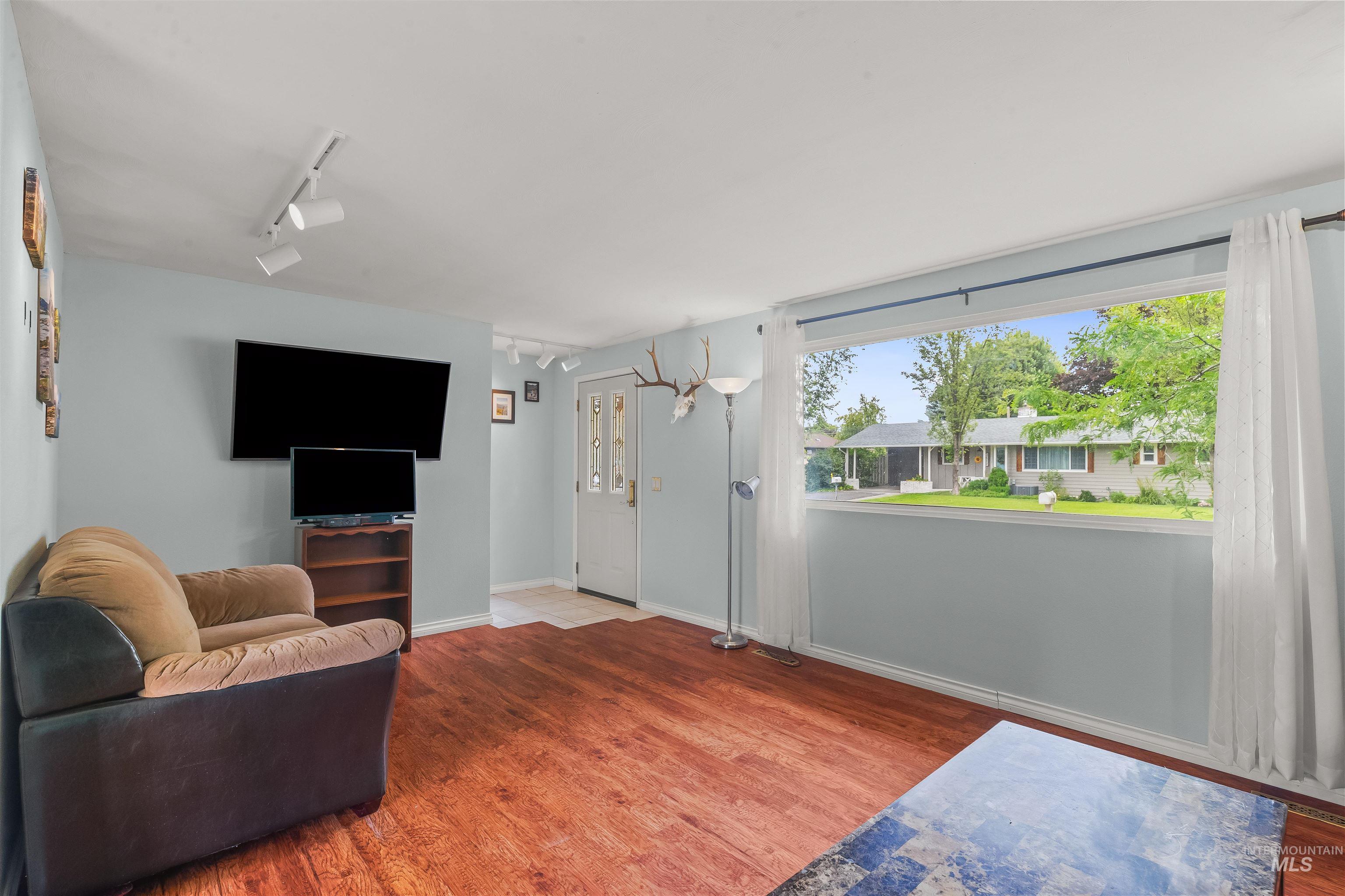 Living area featuring wood-finish flooring, light blue wall paint, and overhead track lighting