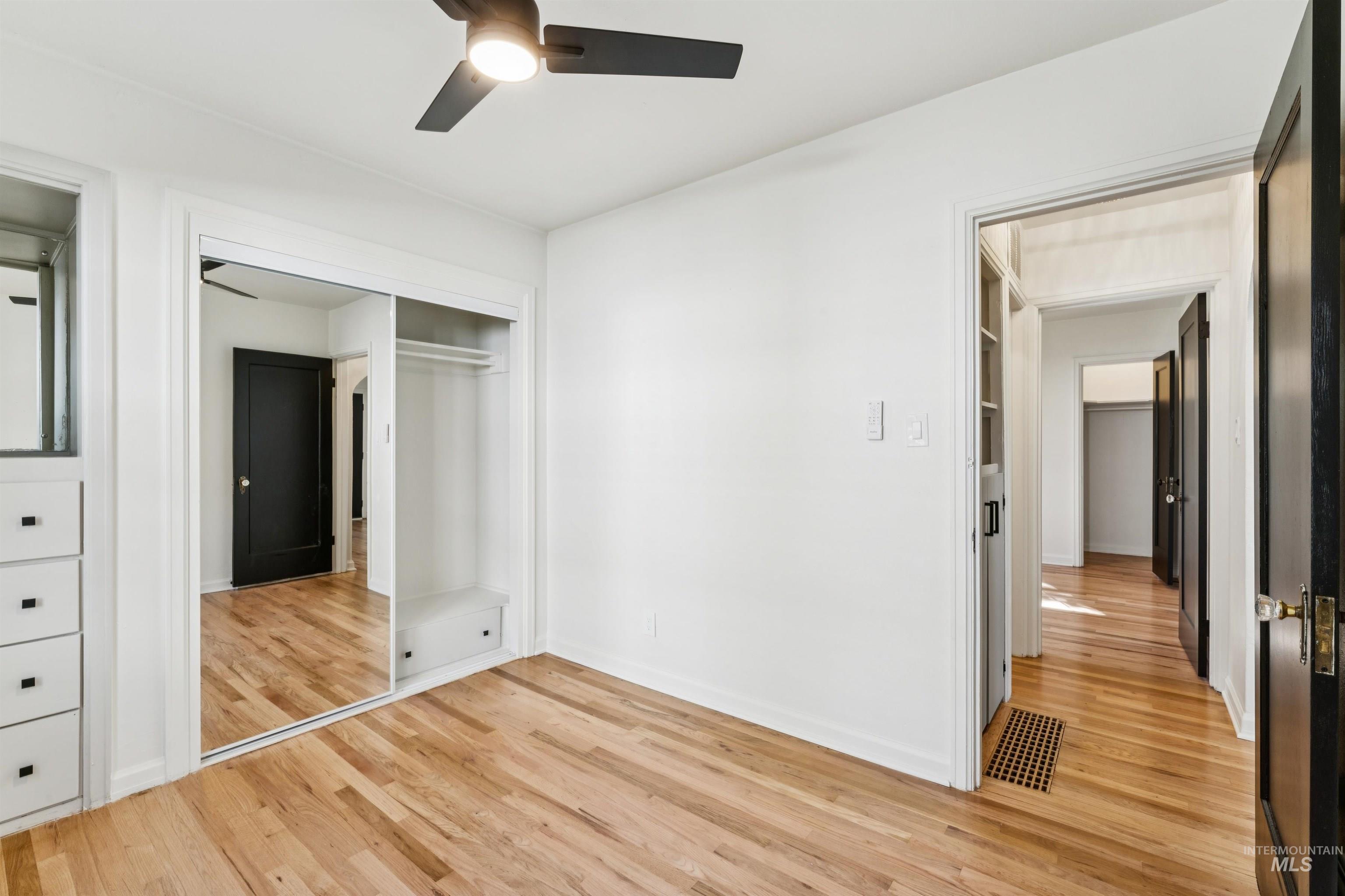 Unfurnished bedroom with light wood-style flooring, a closet, and a ceiling fan