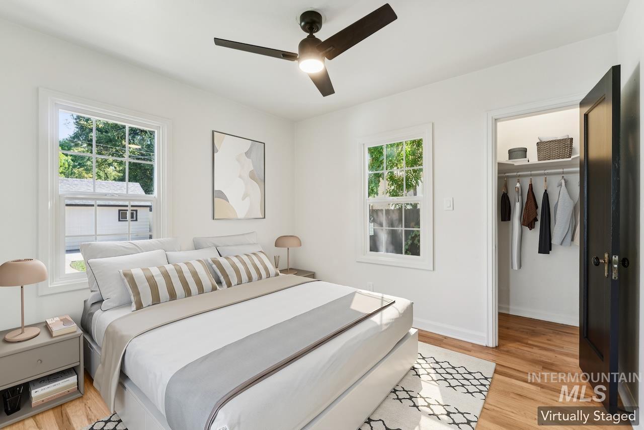 Bedroom with a walk in closet, light wood-style flooring, and a ceiling fan