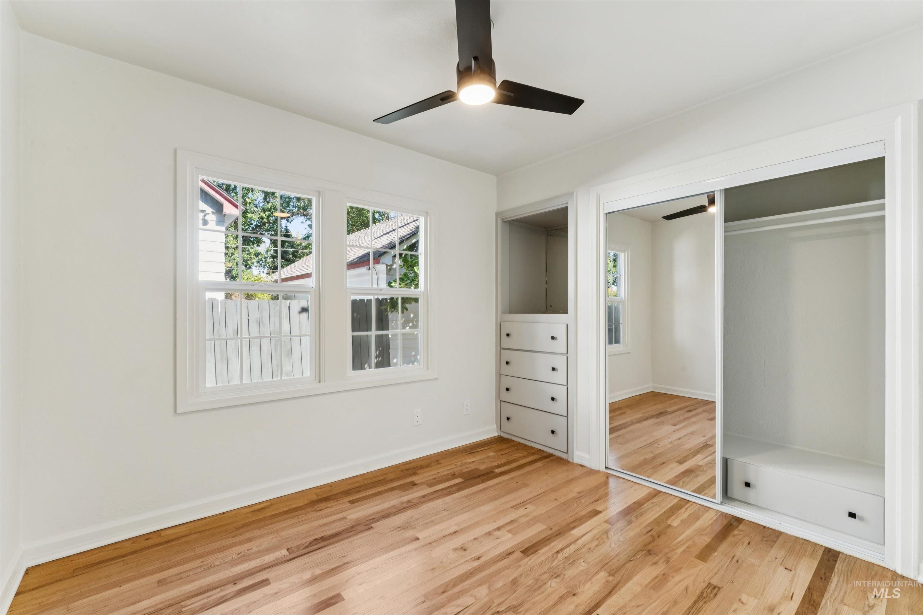 Unfurnished bedroom featuring light wood finished floors, multiple windows, a ceiling fan, and a closet