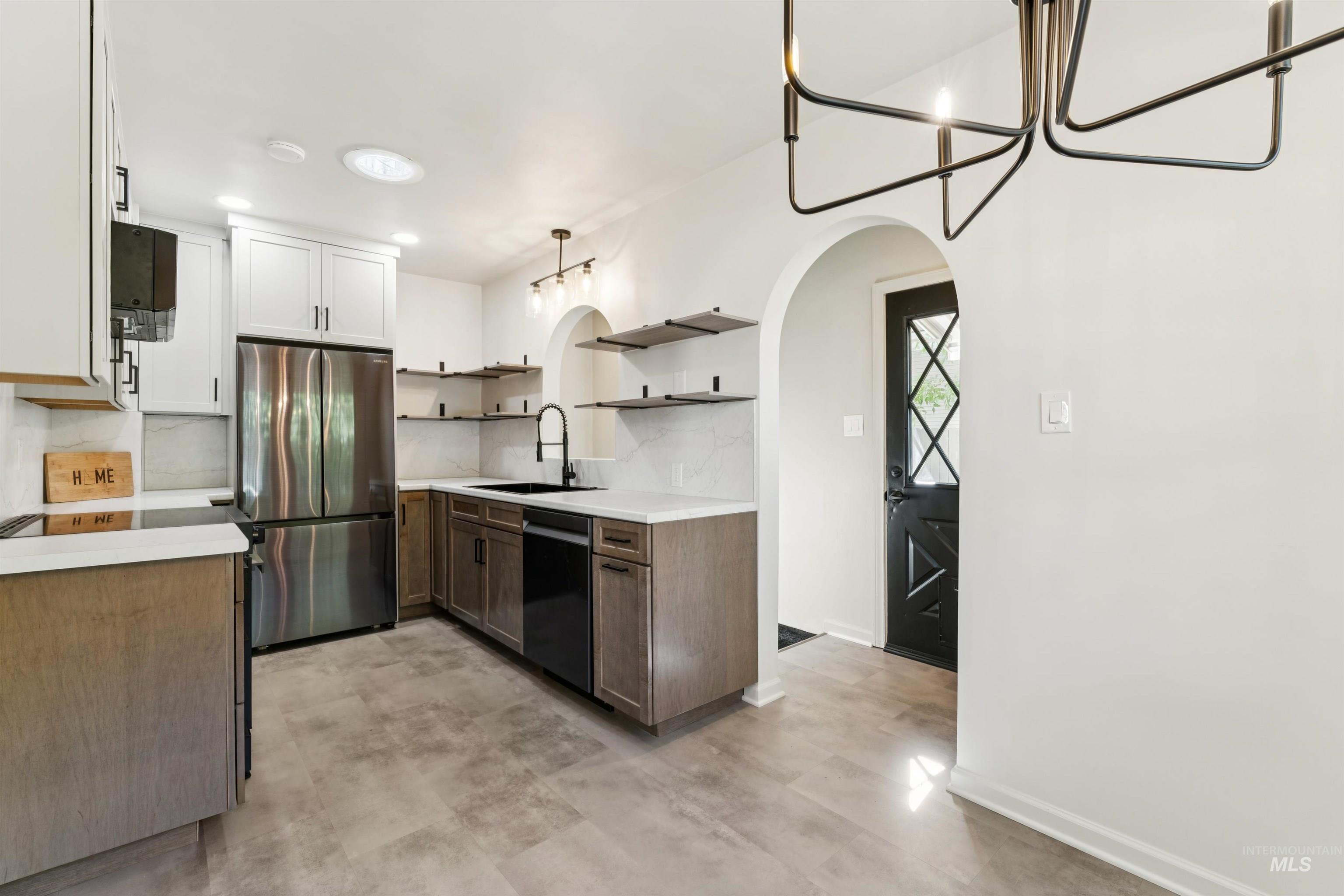 Kitchen with hanging light fixtures, a chandelier, arched walkways, open shelves, and appliances with stainless steel finishes
