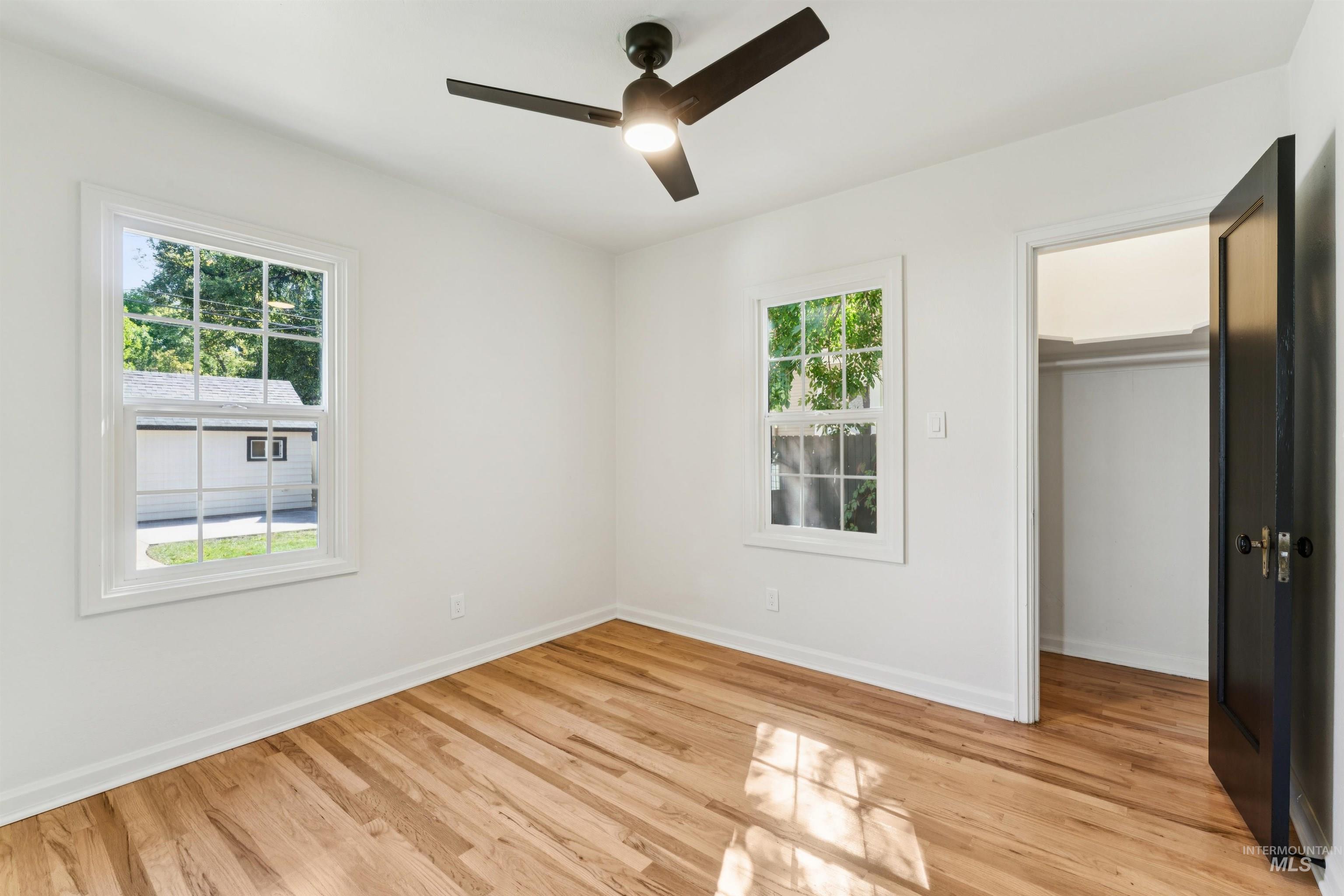 Unfurnished bedroom with ceiling fan, light wood-style flooring, and a walk in closet