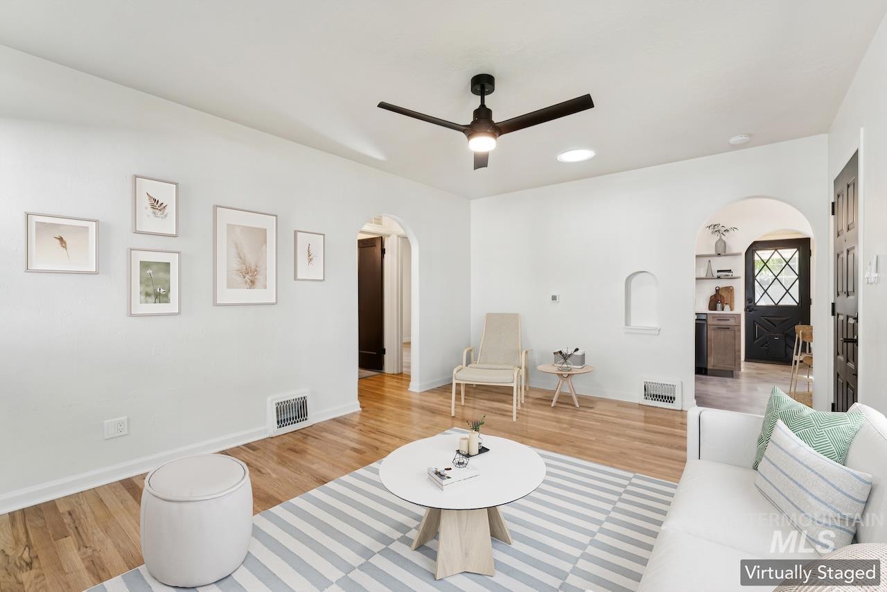 Living room featuring arched walkways, wood finished floors, and a ceiling fan