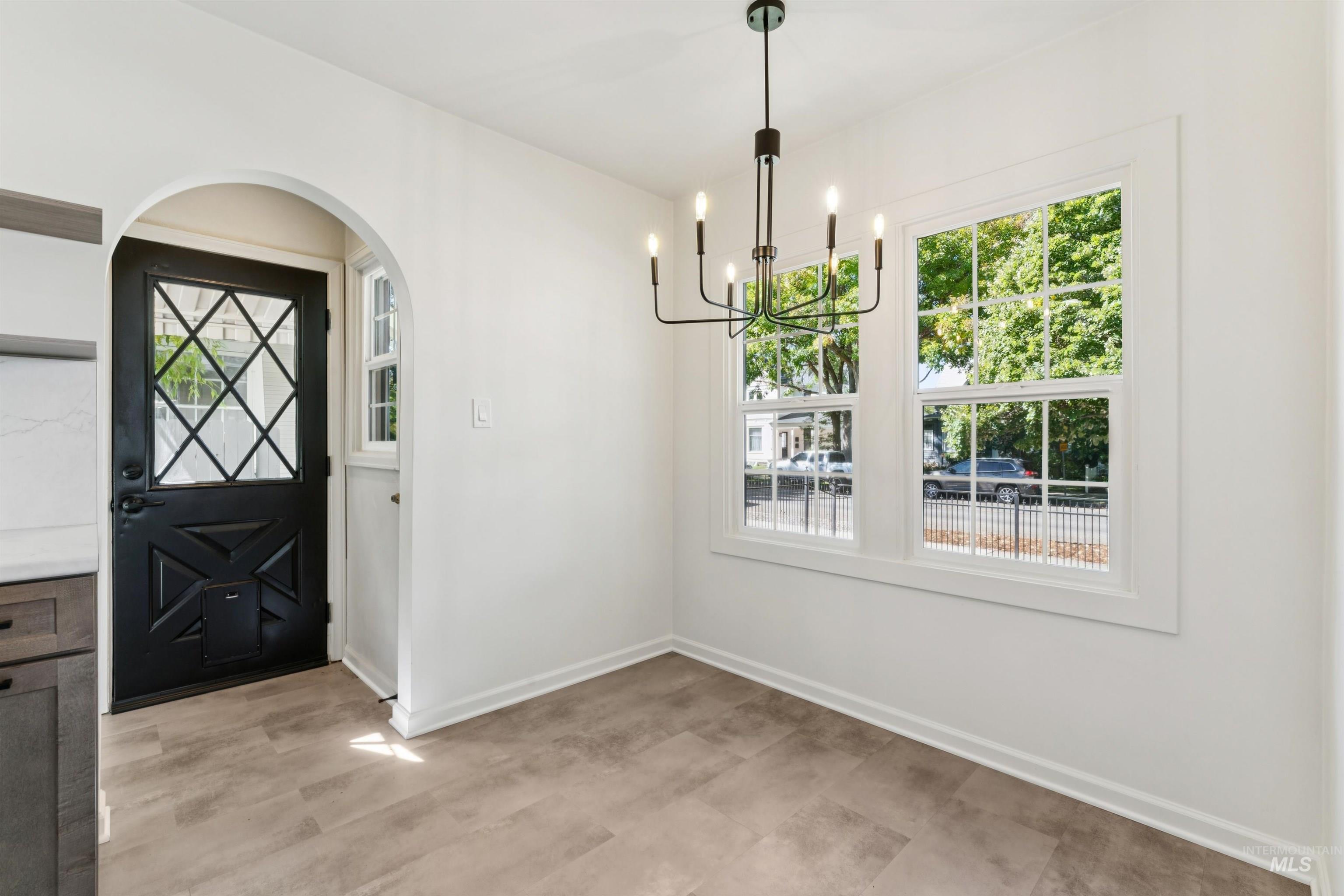 Unfurnished dining area with healthy amount of natural light, arched walkways, and a chandelier