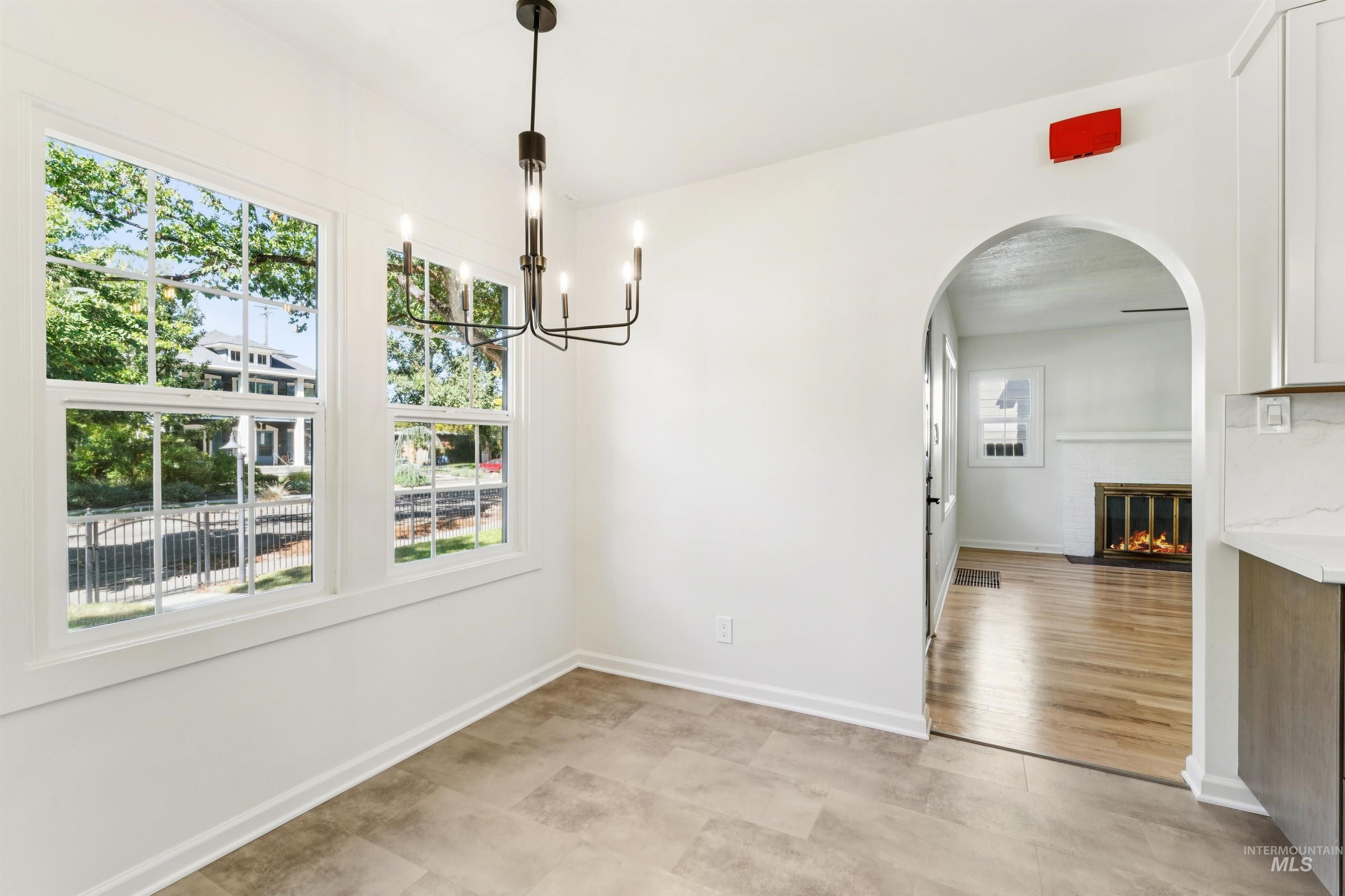 Unfurnished dining area featuring arched walkways, a glass covered fireplace, and a chandelier