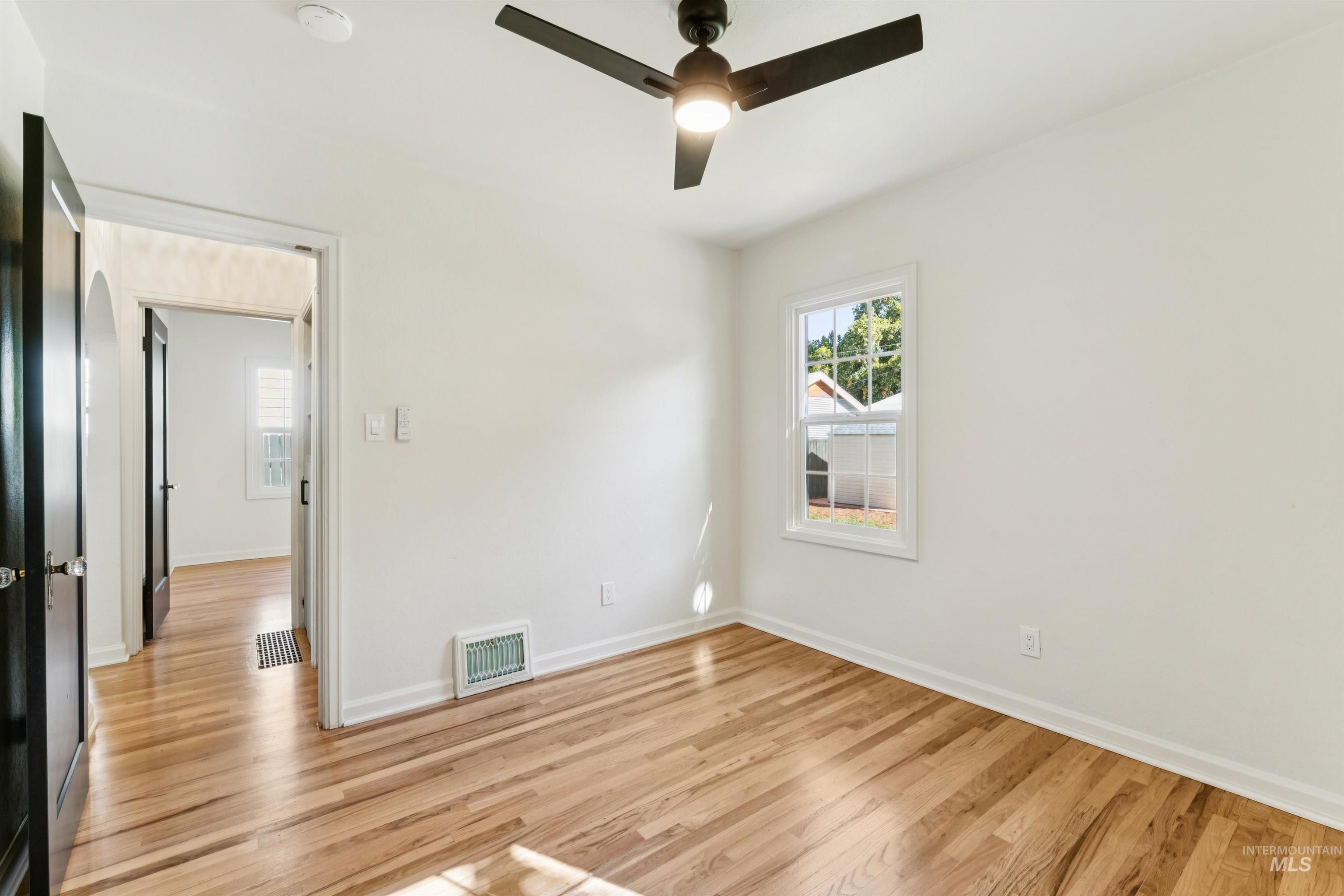 Empty room with light wood-type flooring and a ceiling fan