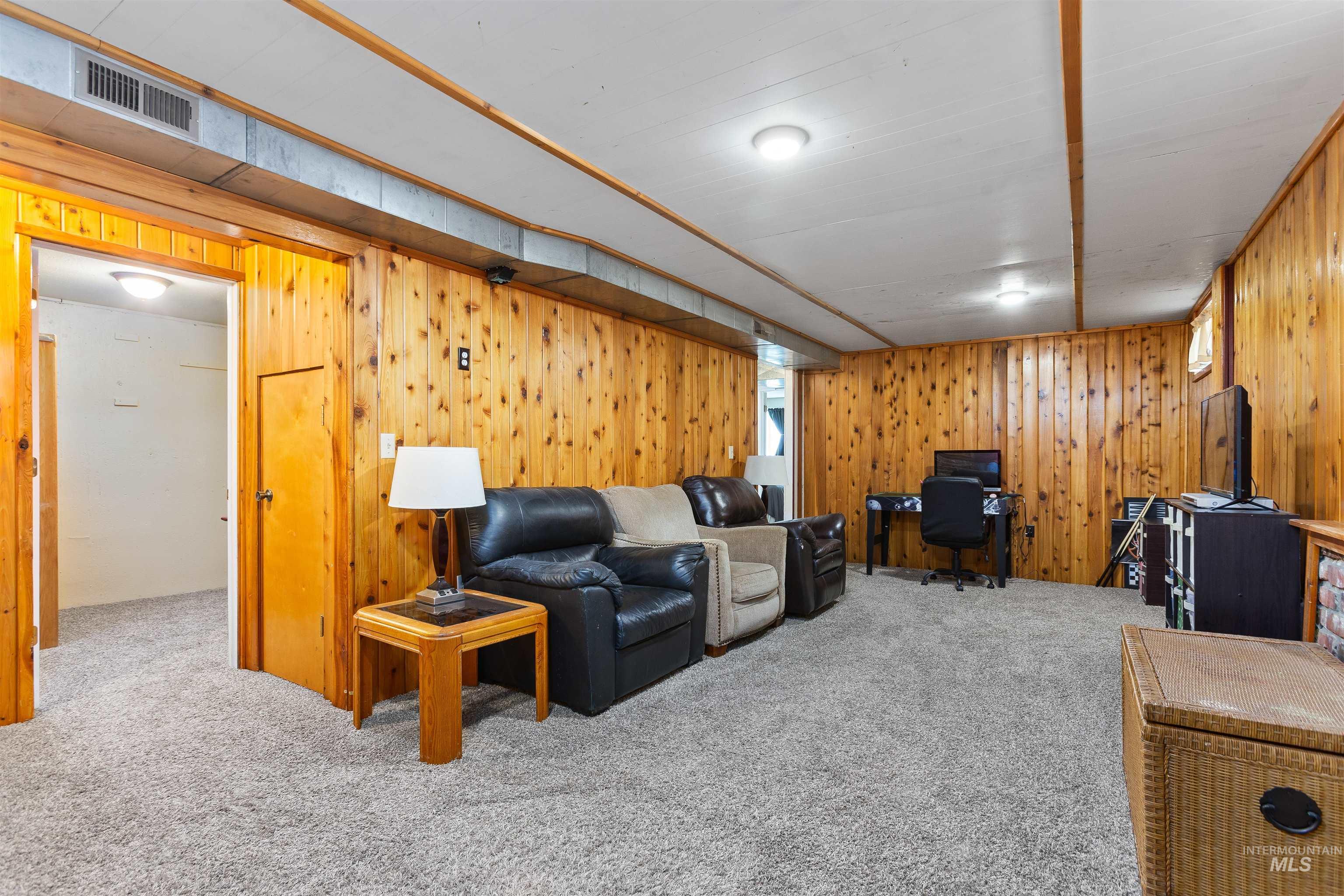 Living area featuring a desk, carpet, and wood walls