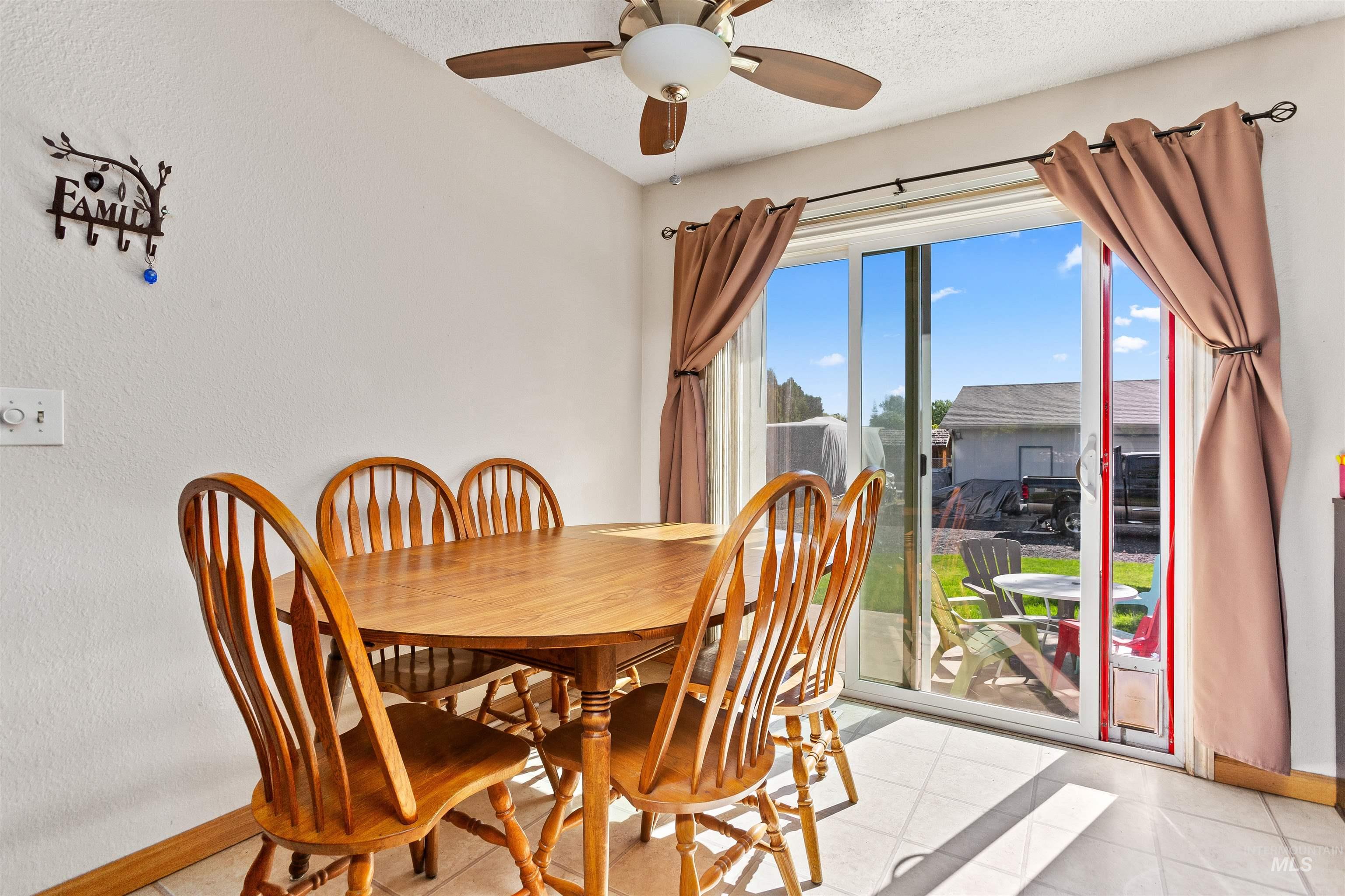 Dining room featuring ceiling fan, a textured ceiling, and light tile patterned floors