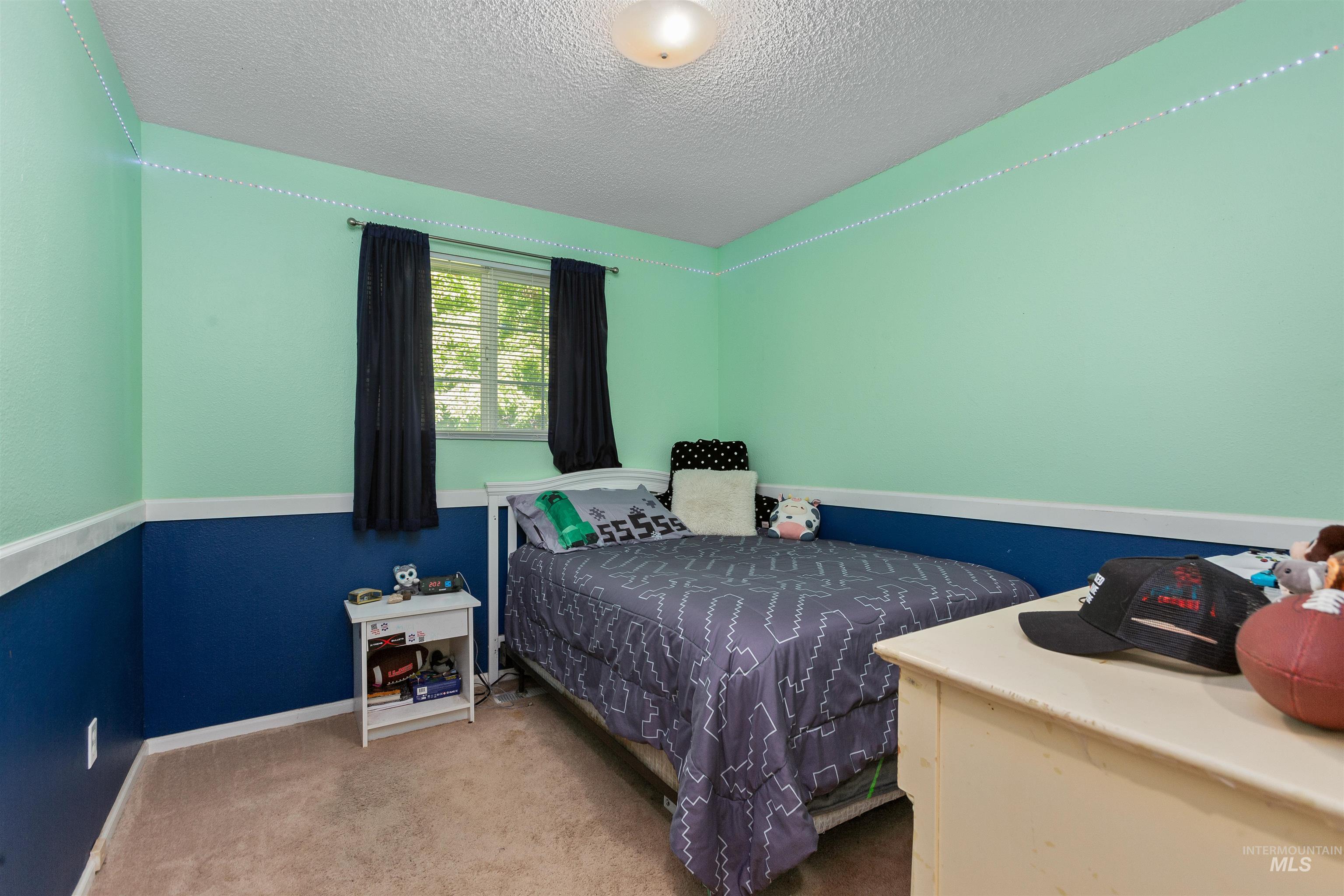 Carpeted bedroom featuring a textured ceiling and baseboards