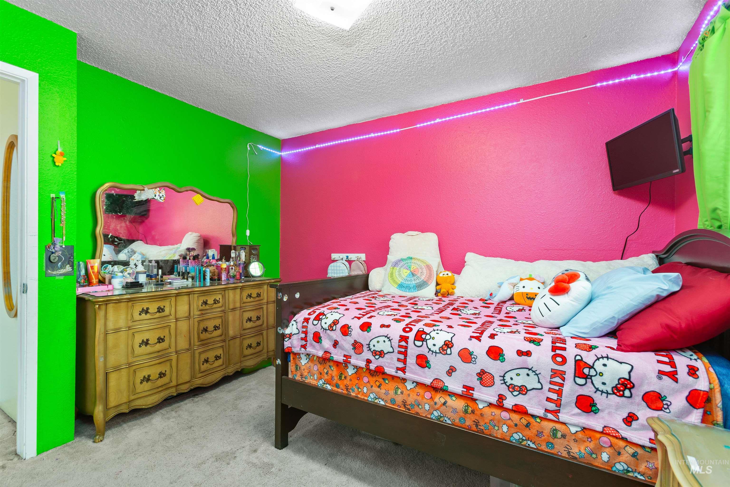 Bedroom with a textured ceiling, light carpet, and a textured wall