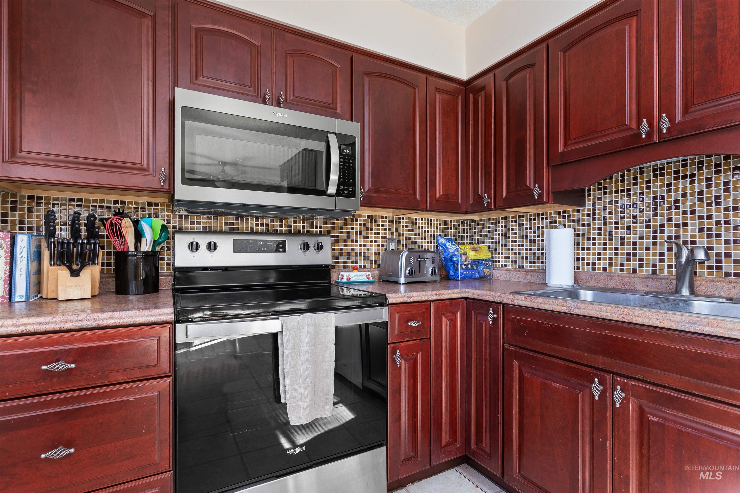 Kitchen featuring reddish brown cabinets and appliances with stainless steel finishes