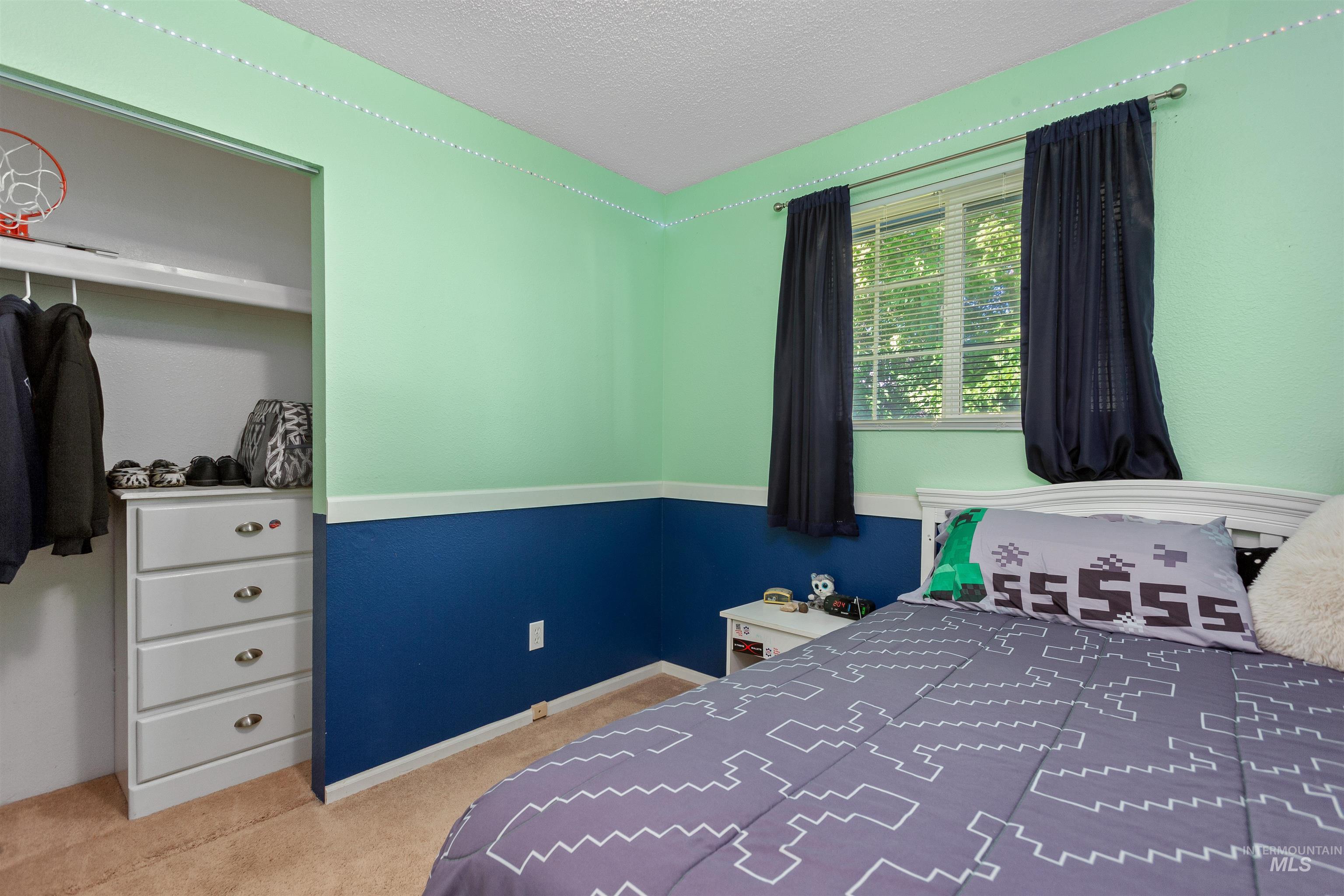 Bedroom with a textured ceiling, light colored carpet, and a closet