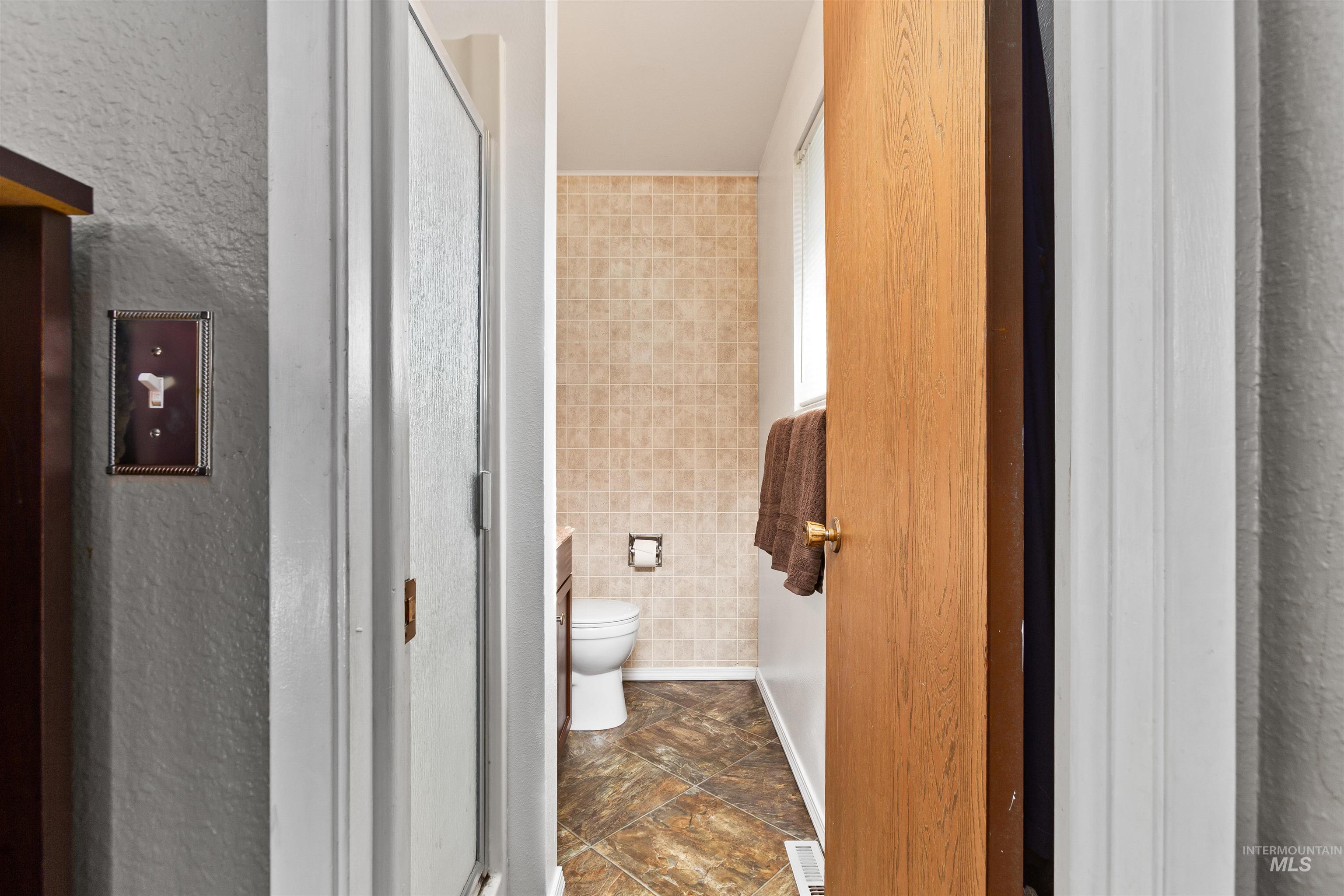 Full bath featuring tile walls and a stall shower