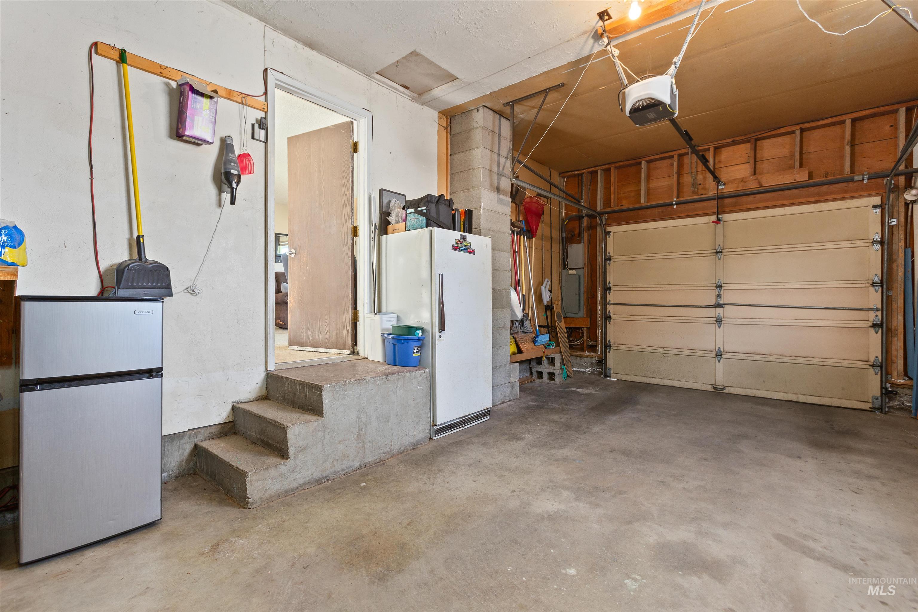 Garage with freestanding refrigerator and a garage door opener