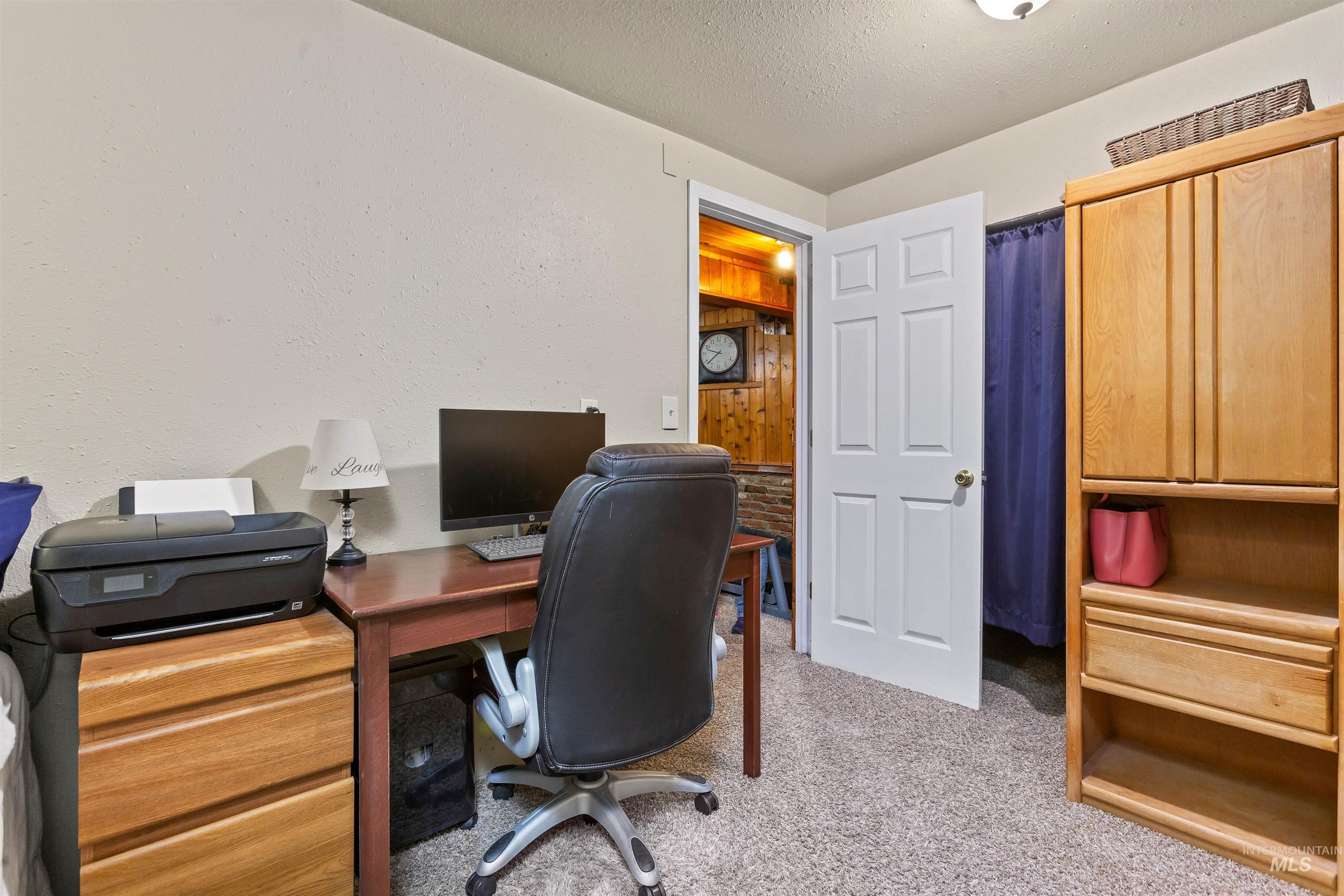 Office with light carpet, a textured ceiling, and a textured wall