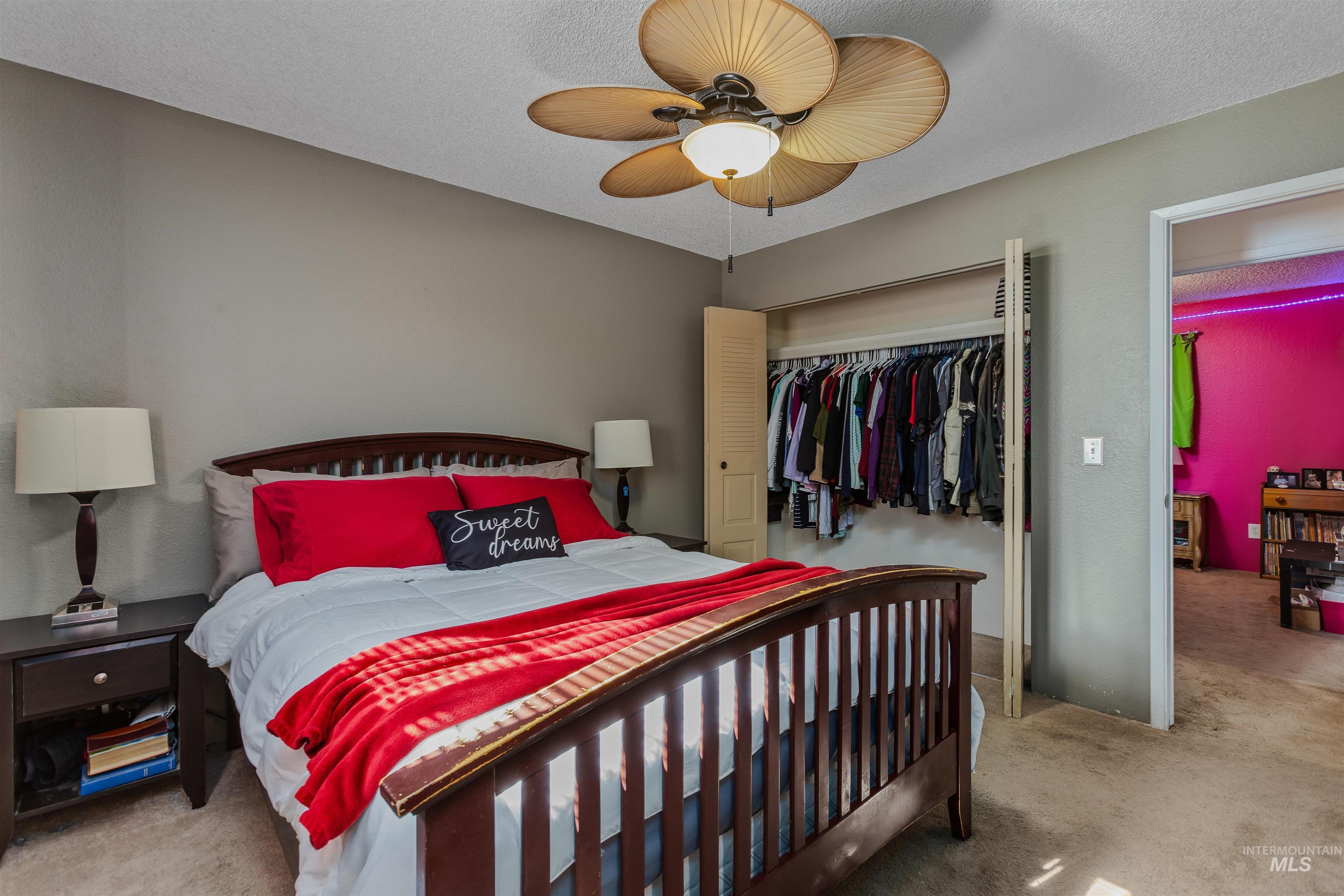 Bedroom with light colored carpet, a closet, a textured ceiling, and ceiling fan