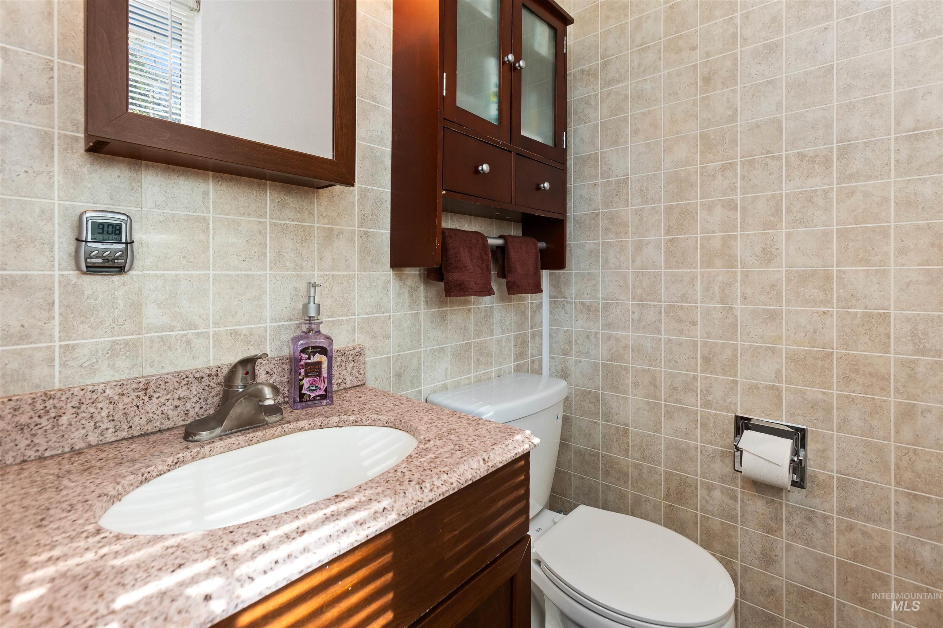 Half bathroom featuring tile walls, vanity, and backsplash