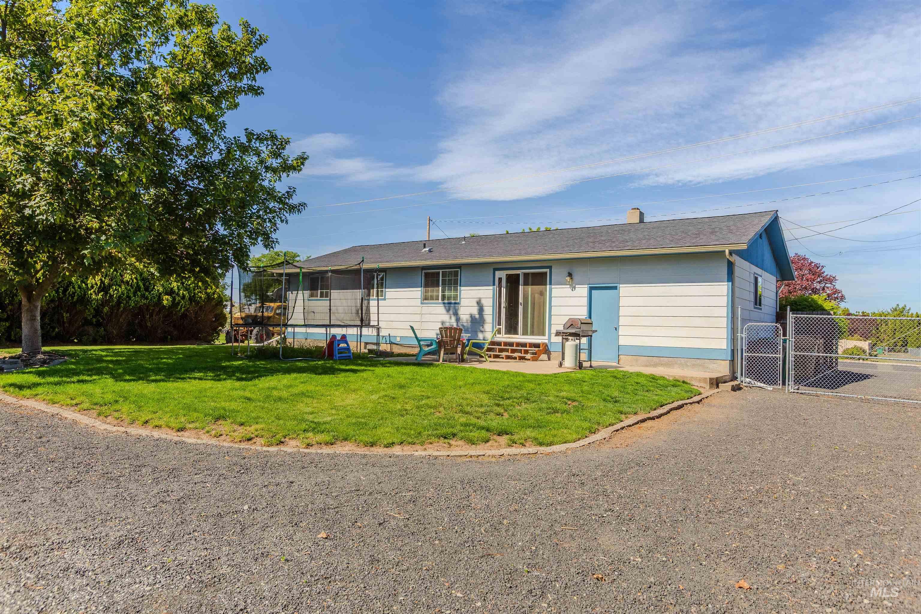 Rear view of property with a gate, a trampoline, a chimney, and a patio