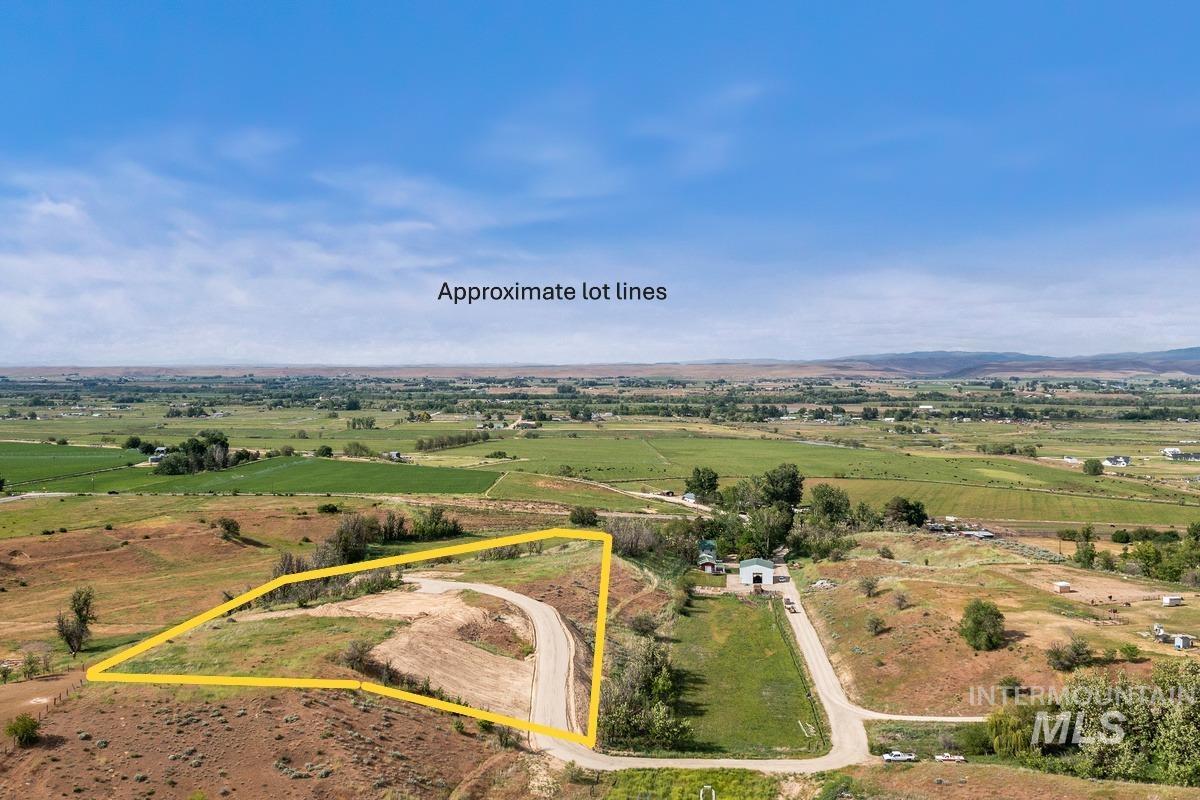 Aerial view of sparsely populated area featuring property parcel outlined and a mountain backdrop