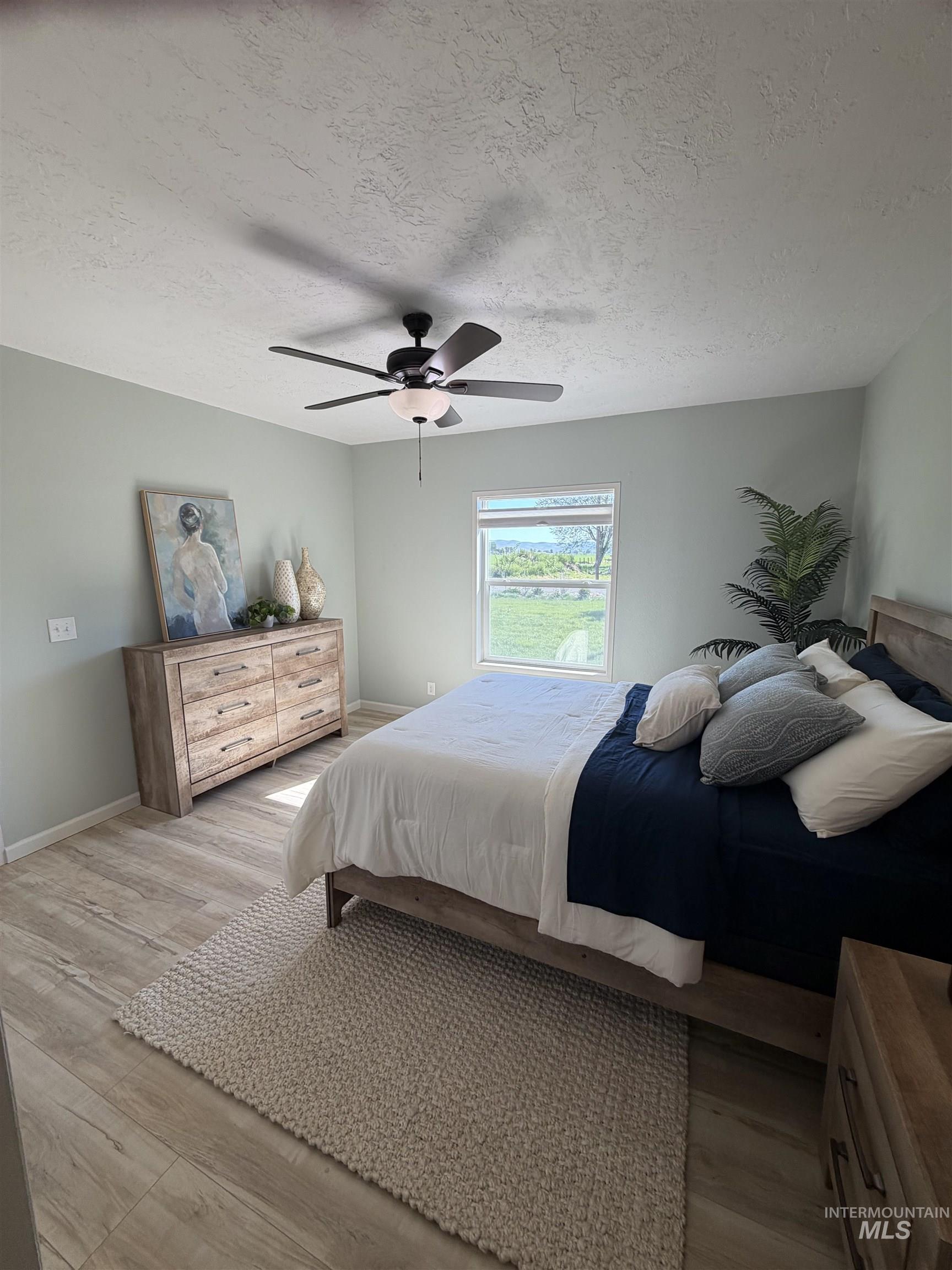 Spacious room featuring wood-finish flooring, light-toned walls, and a ceiling fan with integrated lighting