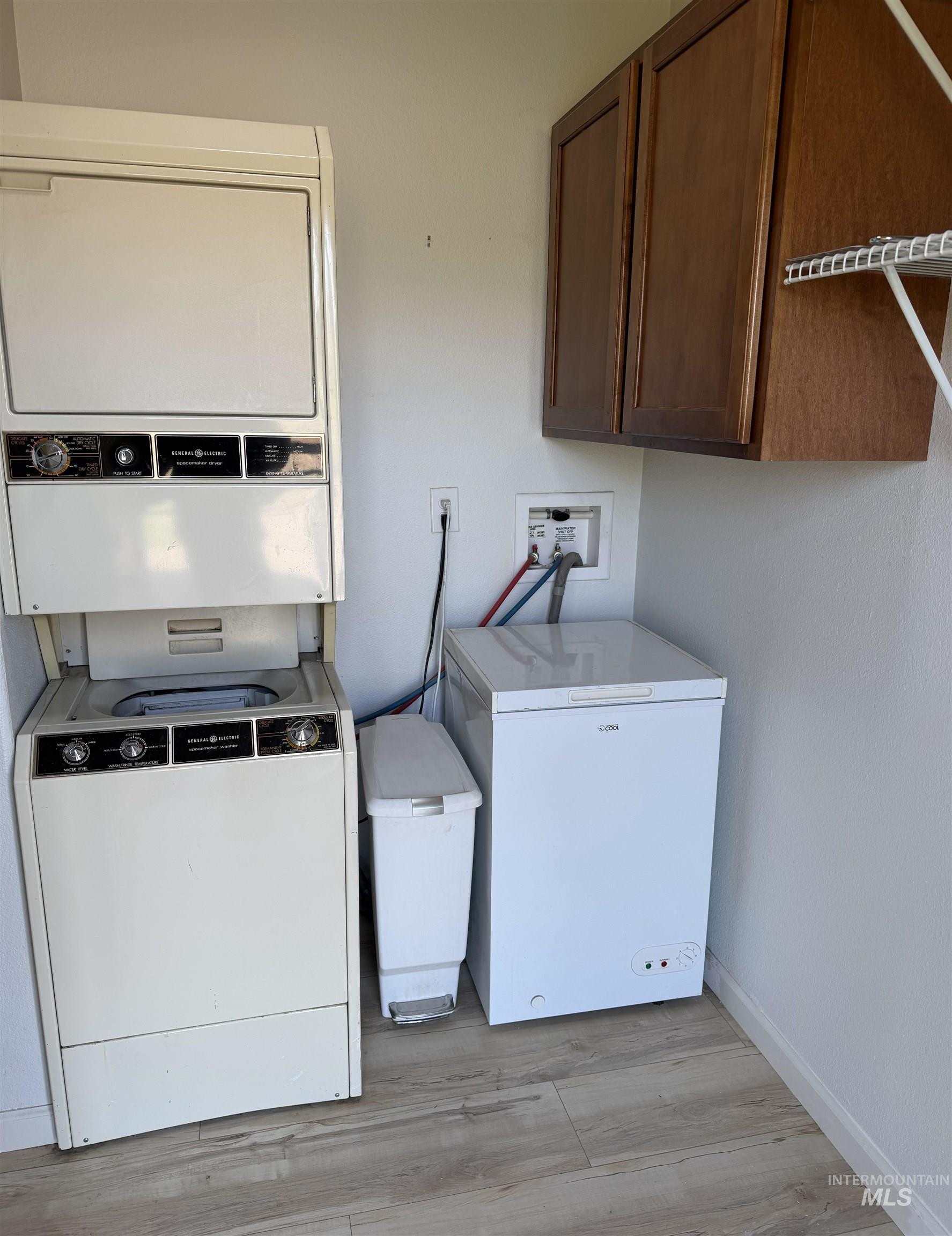 Laundry area featuring wood-finish flooring, wall-mounted cabinetry, and a utility hookup