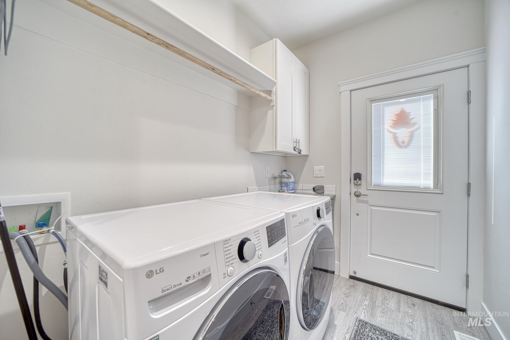 Laundry area with light wood-style flooring, washing machine and clothes dryer, and cabinet space
