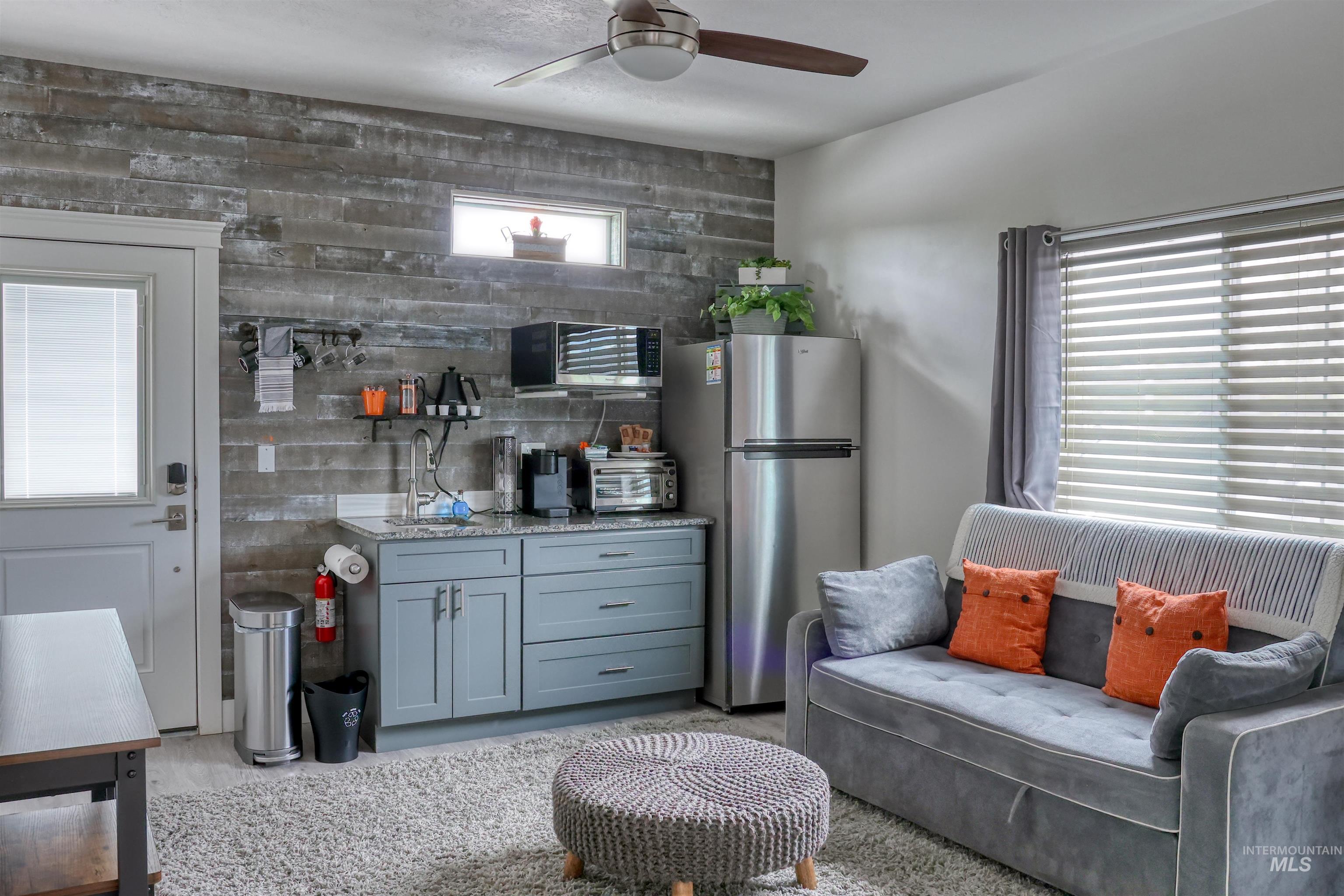 Kitchen featuring stainless steel appliances, light stone countertops, a ceiling fan, and gray cabinets