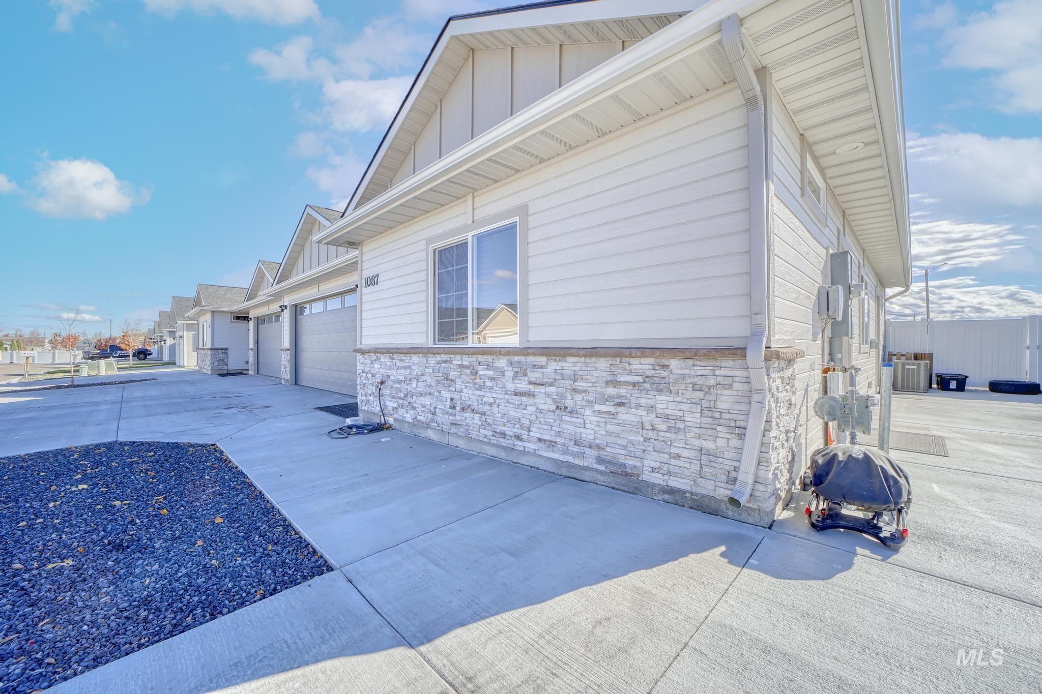 View of property exterior featuring stone siding, concrete driveway, and board and batten siding