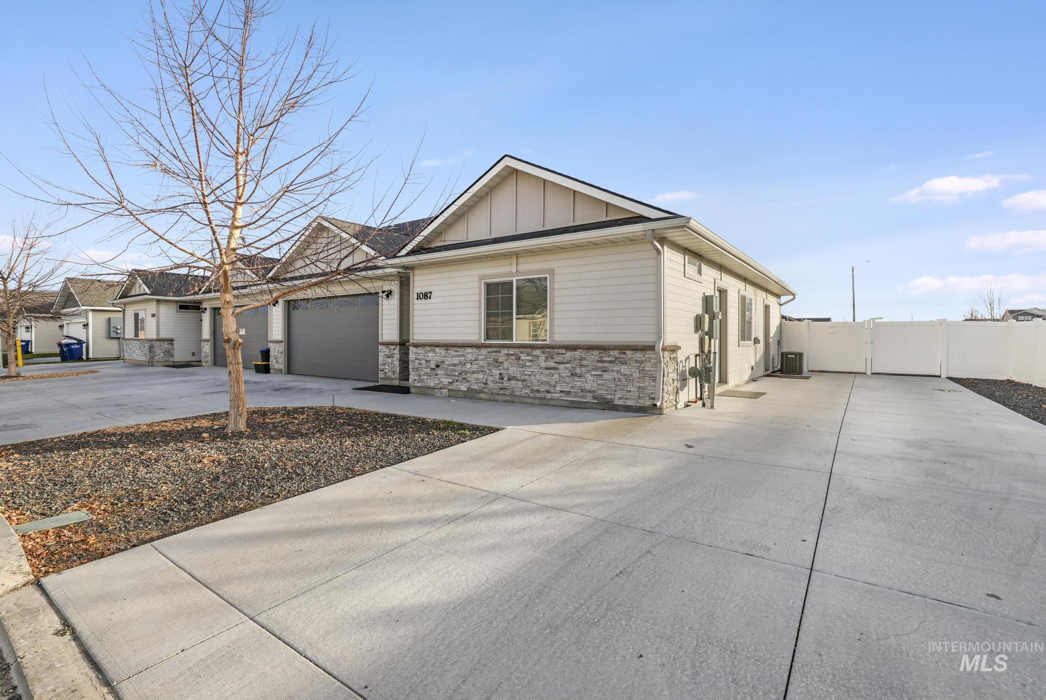 View of front of house featuring driveway, board and batten siding, stone siding, and a garage