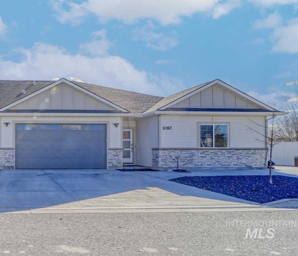 View of front of property featuring board and batten siding, stone siding, driveway, a garage, and a shingled roof