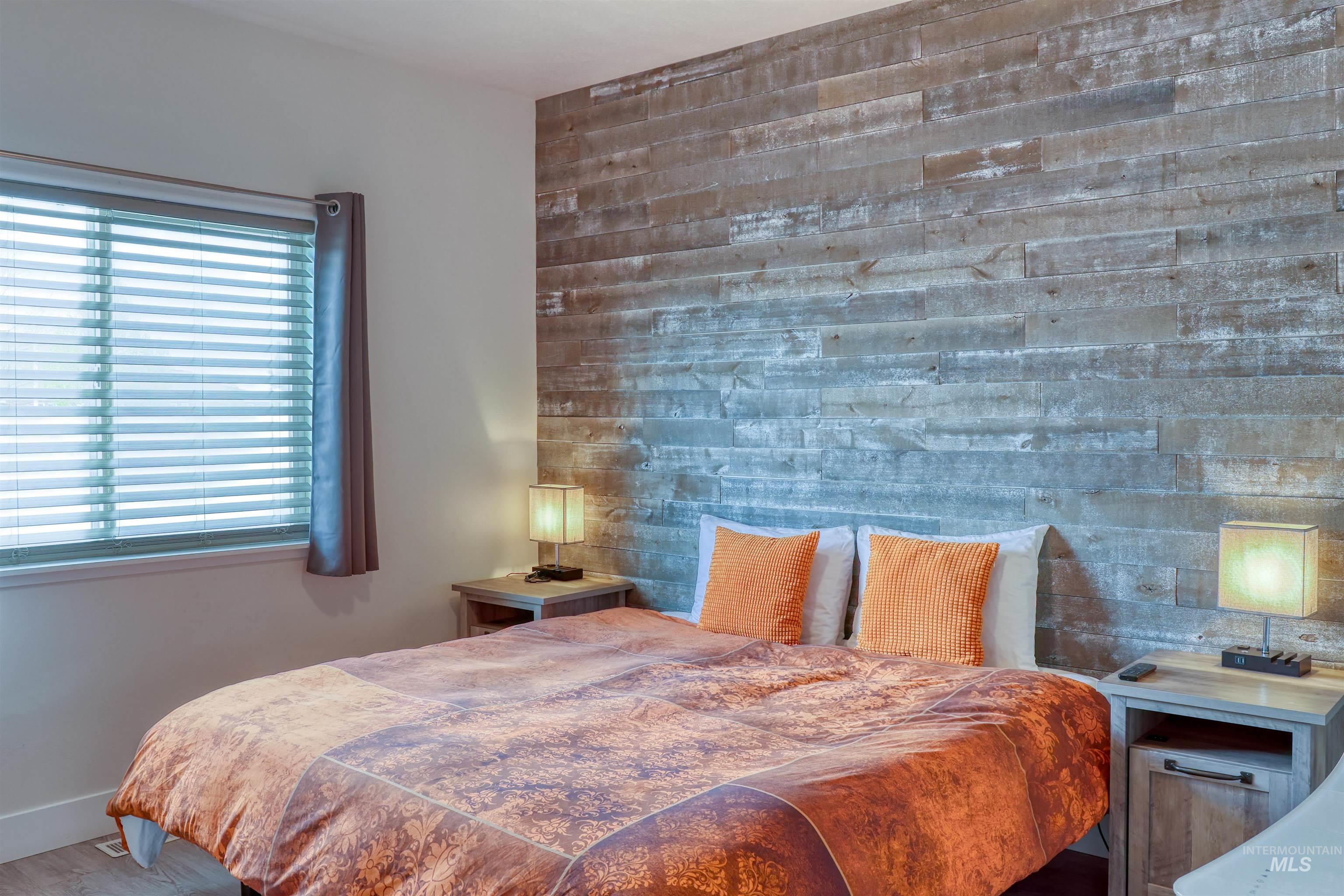 Bedroom with an accent wall and wood finished floors