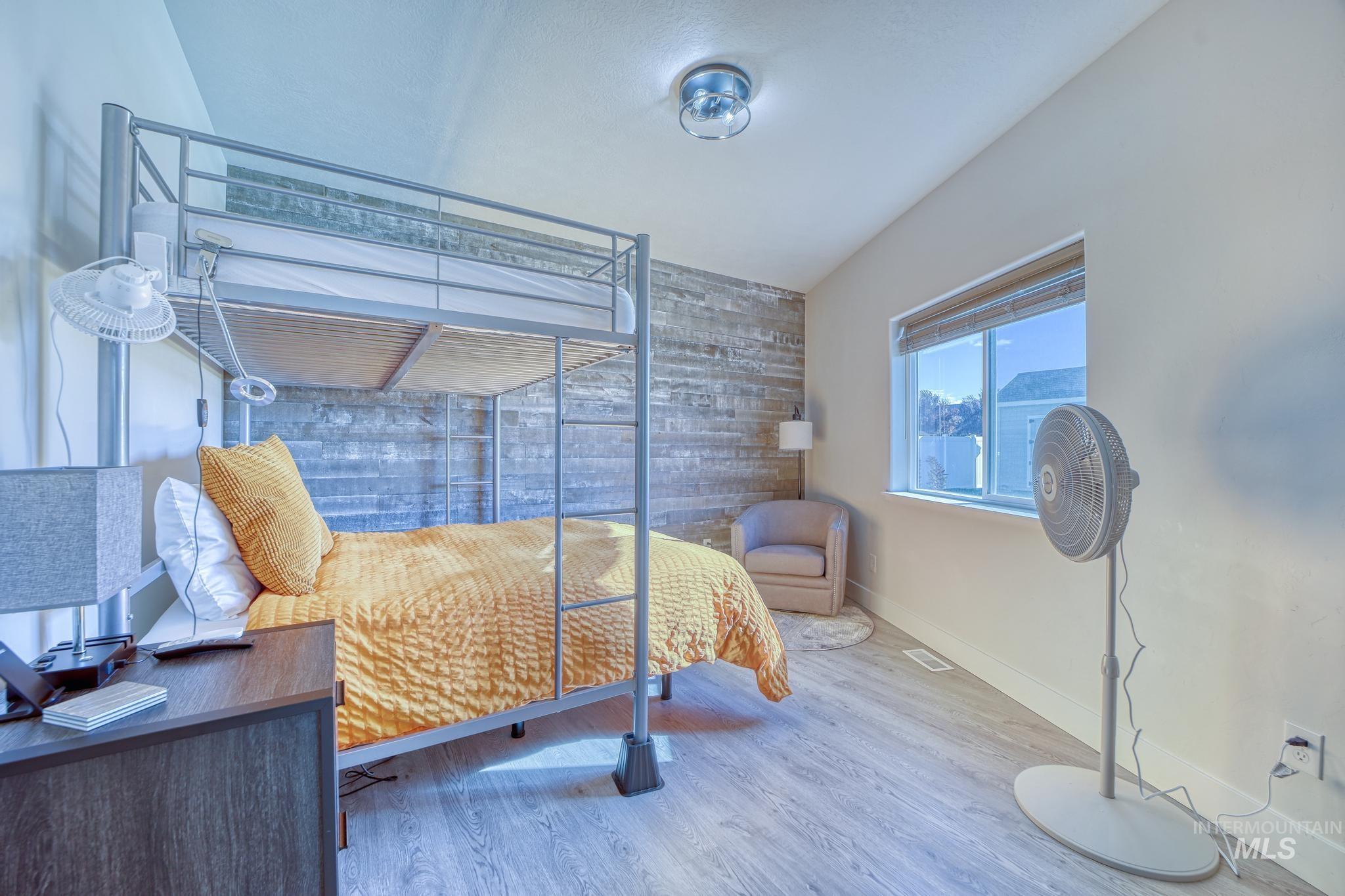 Bedroom featuring wood finished floors, wooden walls, and lofted ceiling