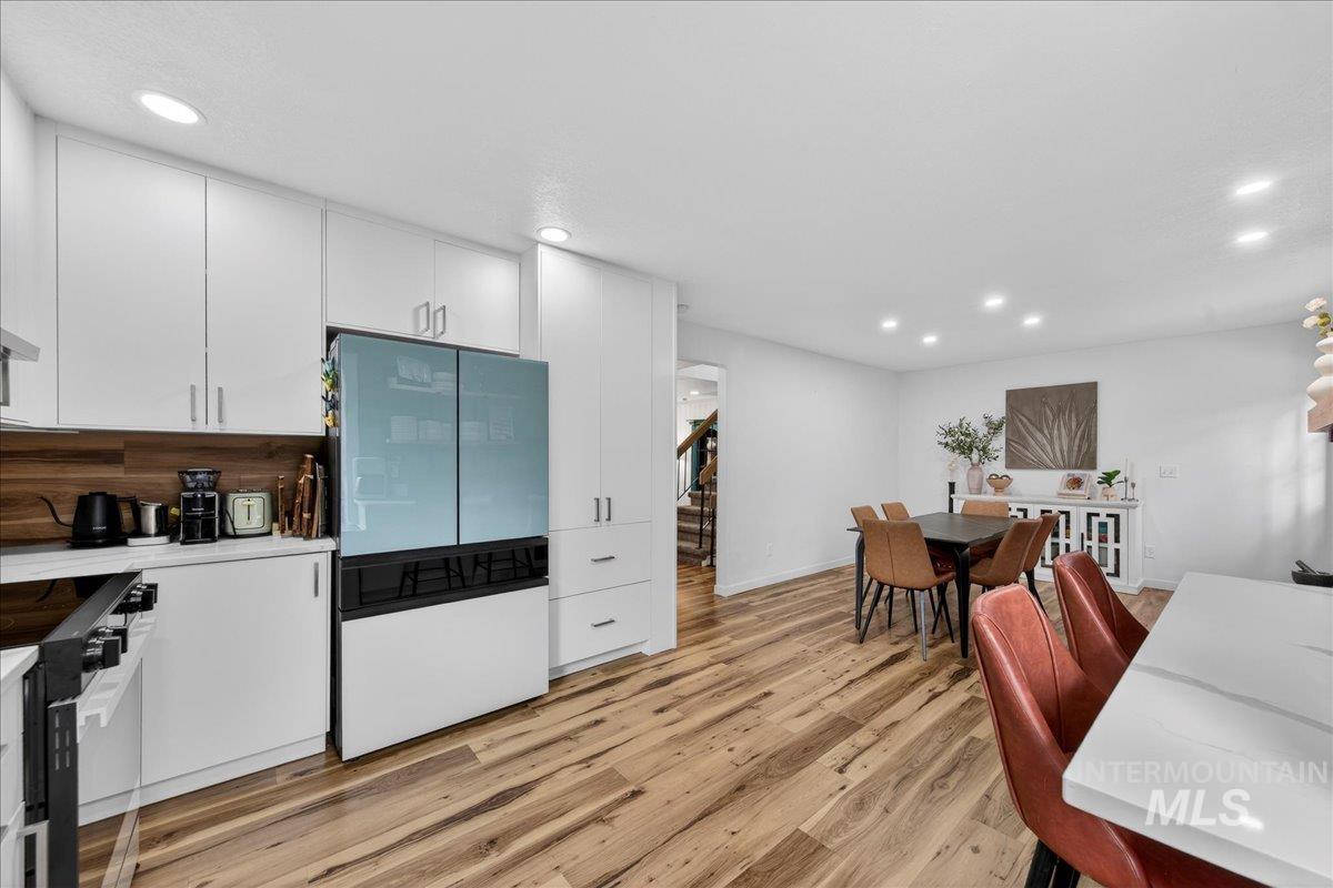 Kitchen with white cabinets, freestanding refrigerator, black range with electric cooktop, recessed lighting, and light wood-type flooring