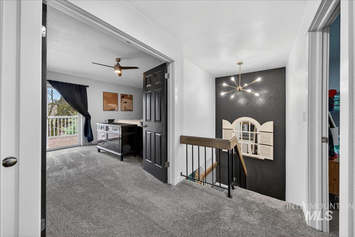 Hallway featuring an upstairs landing, a chandelier, carpet floors, and a textured ceiling